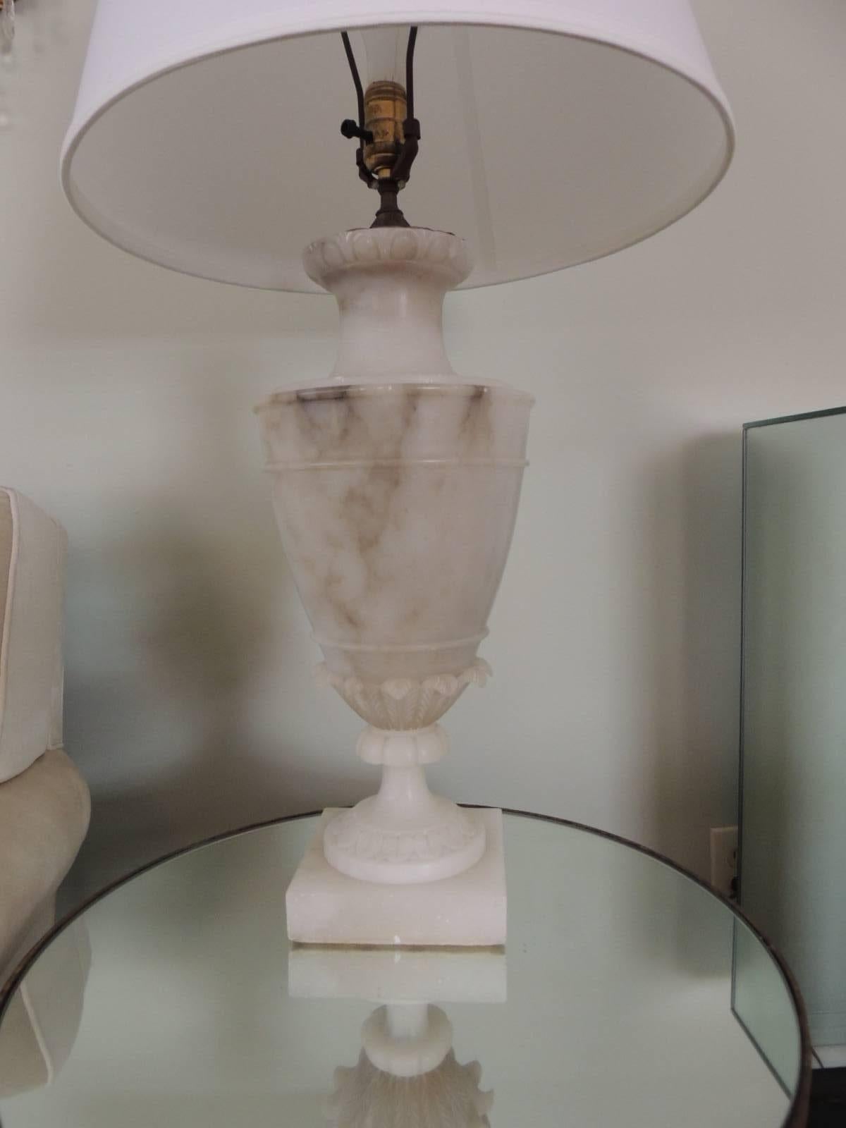 Tall Alabaster Table Lamp in Grey and White,accentuated with small leaves relief and small fluted pedestal base.  Three way switch , no shade,harp and finial included. The top of the lamp has an intricate base cover in antique brass.
Note: small