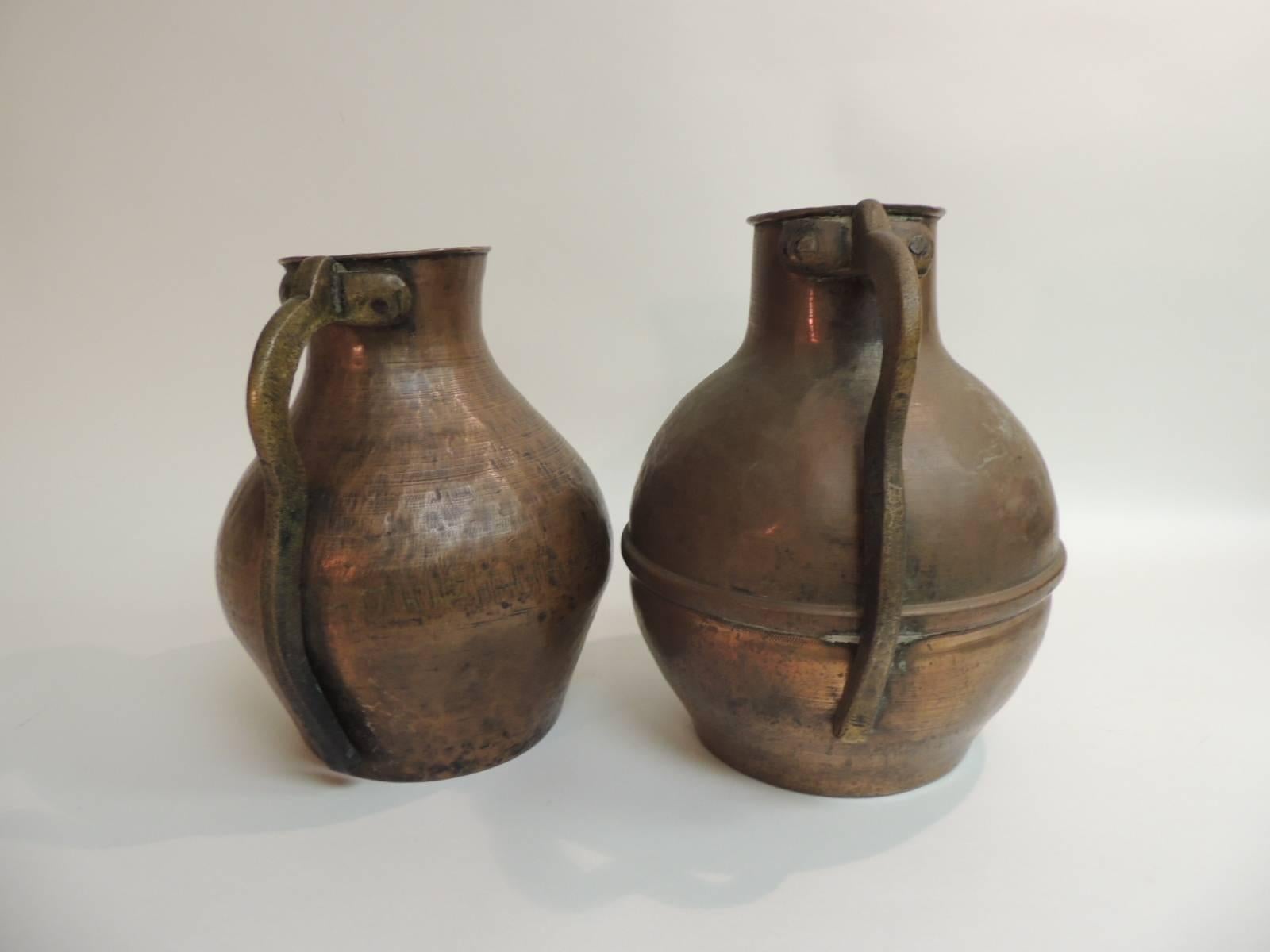 Offered by the Antique Textiles Galleries:
Pair of Heavy Patina Persian Copper Water Jugs with Handles
Pair of heavy patinated Persian copper water jugs with handles. Heavy thick textured copper with thick patinated brass handles.
Size: (right) 10 x