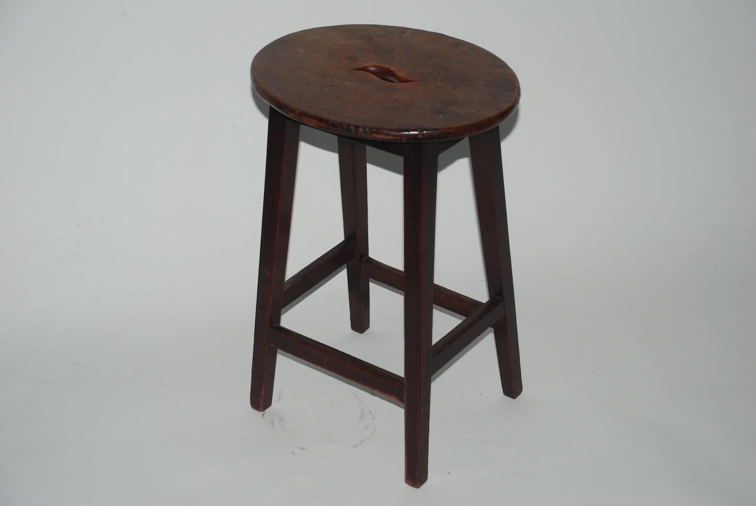 Victorian mahogany stool. The oval overhang top pierced with S-form carrying handle, on flared legs joined by box stretchers.
