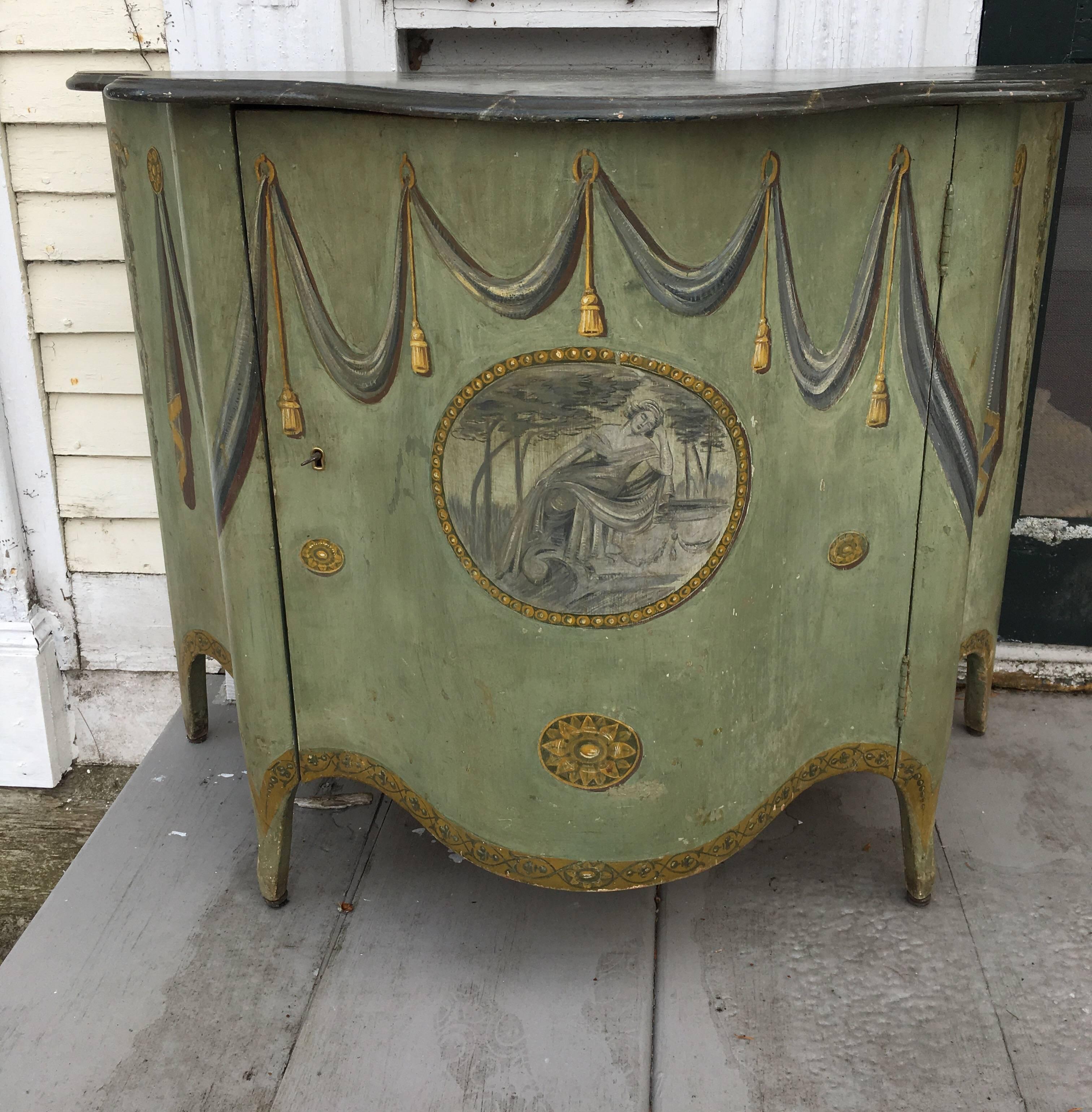 Charmingly painted in a soft grey-green, a George III-style side cabinet with faux marble painted top. Scalloped shape front. Centre door adorned with a painted medallion of a fainting lady. Cabinet decorated with grey swags and yellow tassels,