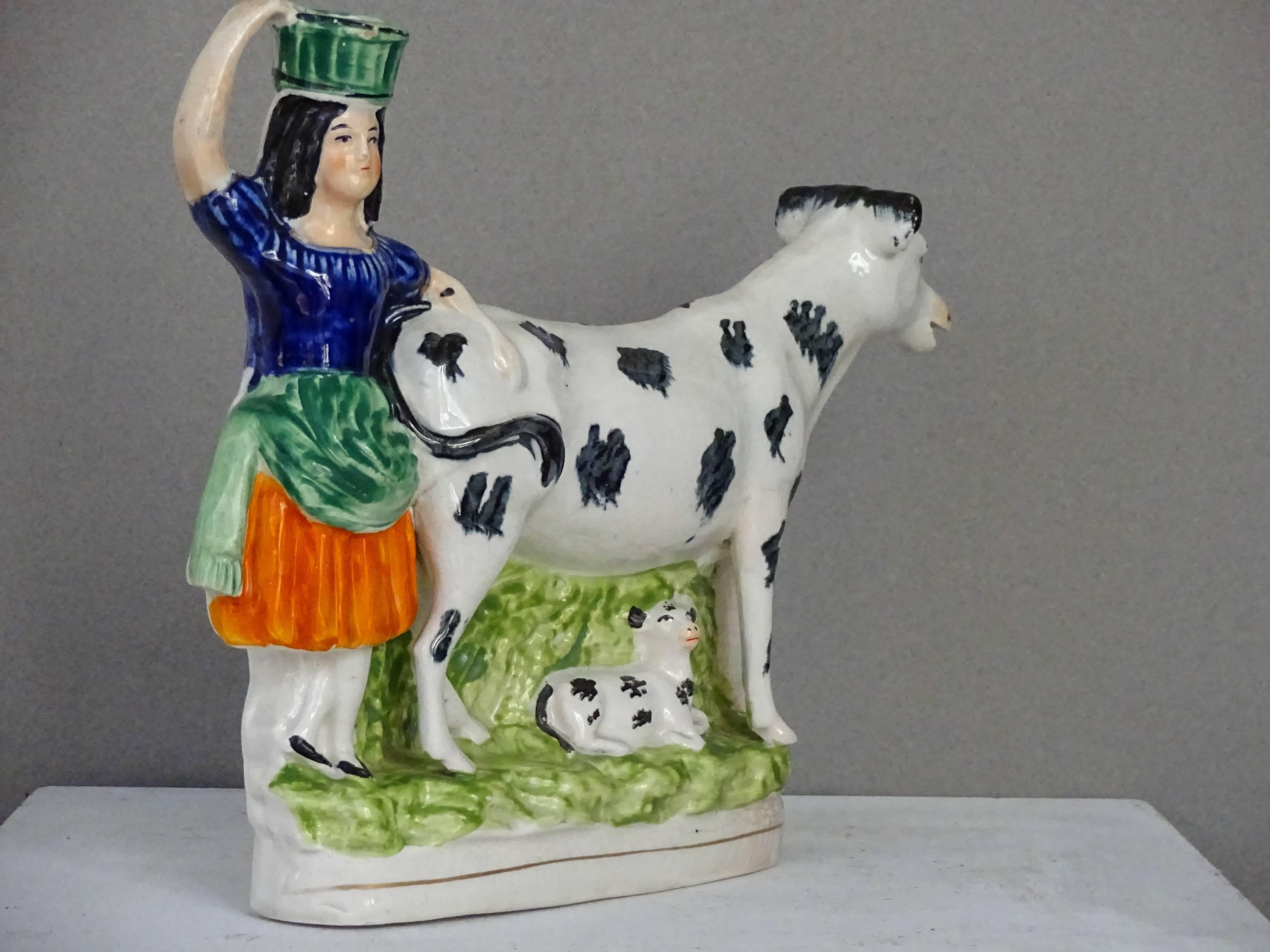 Mid-19th century Staffordshire figural cow creamer with milkmaid and calf.
Maiden has spill vase on her head.