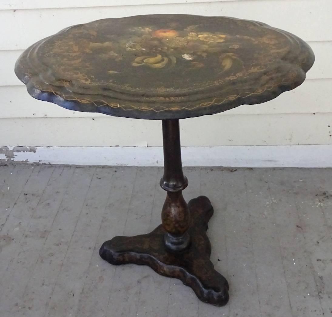 Victorian English papier mâché japanned tilt-top tripod table with inlaid mother of pearl decoration. Beautifully hand- painted flowers decorate the top and gold scrollwork on the turned and tripod base. There were a number of papier mâché makers at