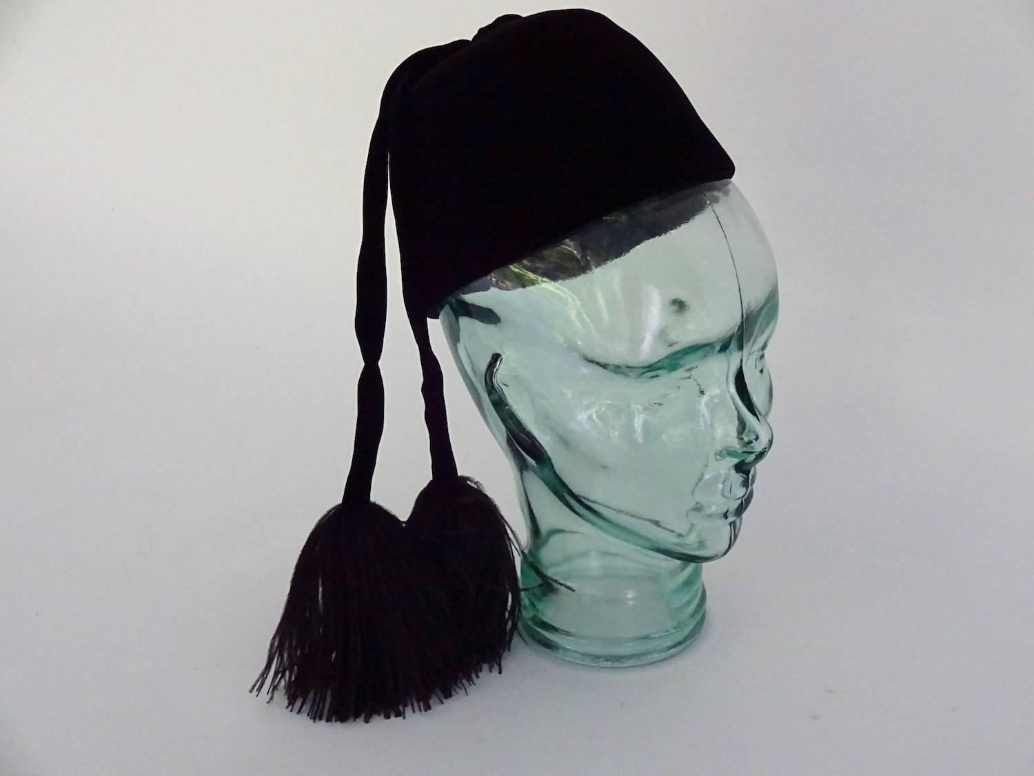 Elegant little black velvet vintage evening toque by Jean Patou with velvet tassels ending in marabou feather trim, circa 1960. Worn at the back of the
head. Combs inside the hatband to keep it in place. Remarkably good condition no wear at all to