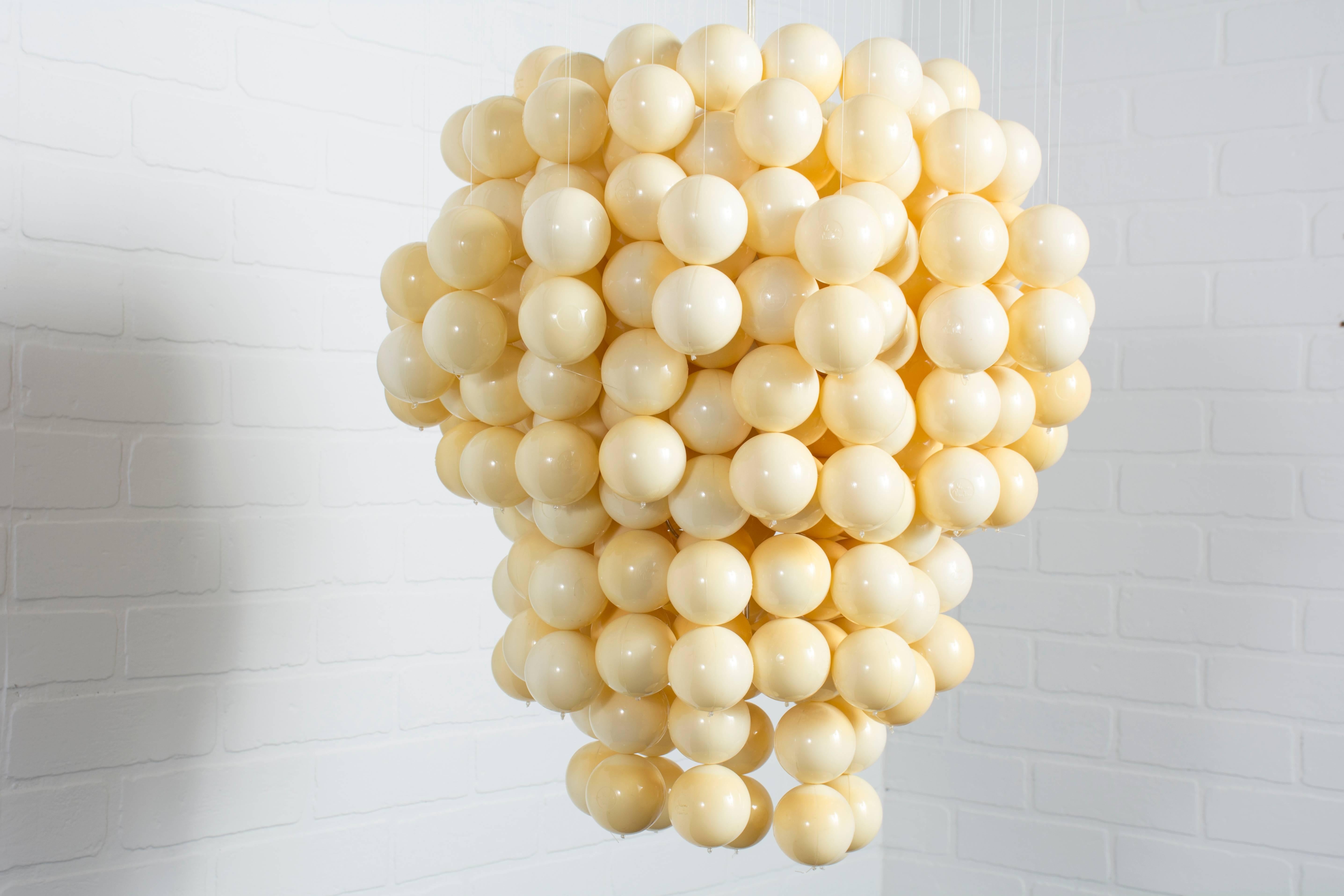 This ball pendant lamp was designed by Verner Panton in the 1960s. It features many yellow balls that hang from a white ceiling plate that is signed Verner Panton. The balls hang symmetrically when suspended from the ceiling (we hung it from a chain