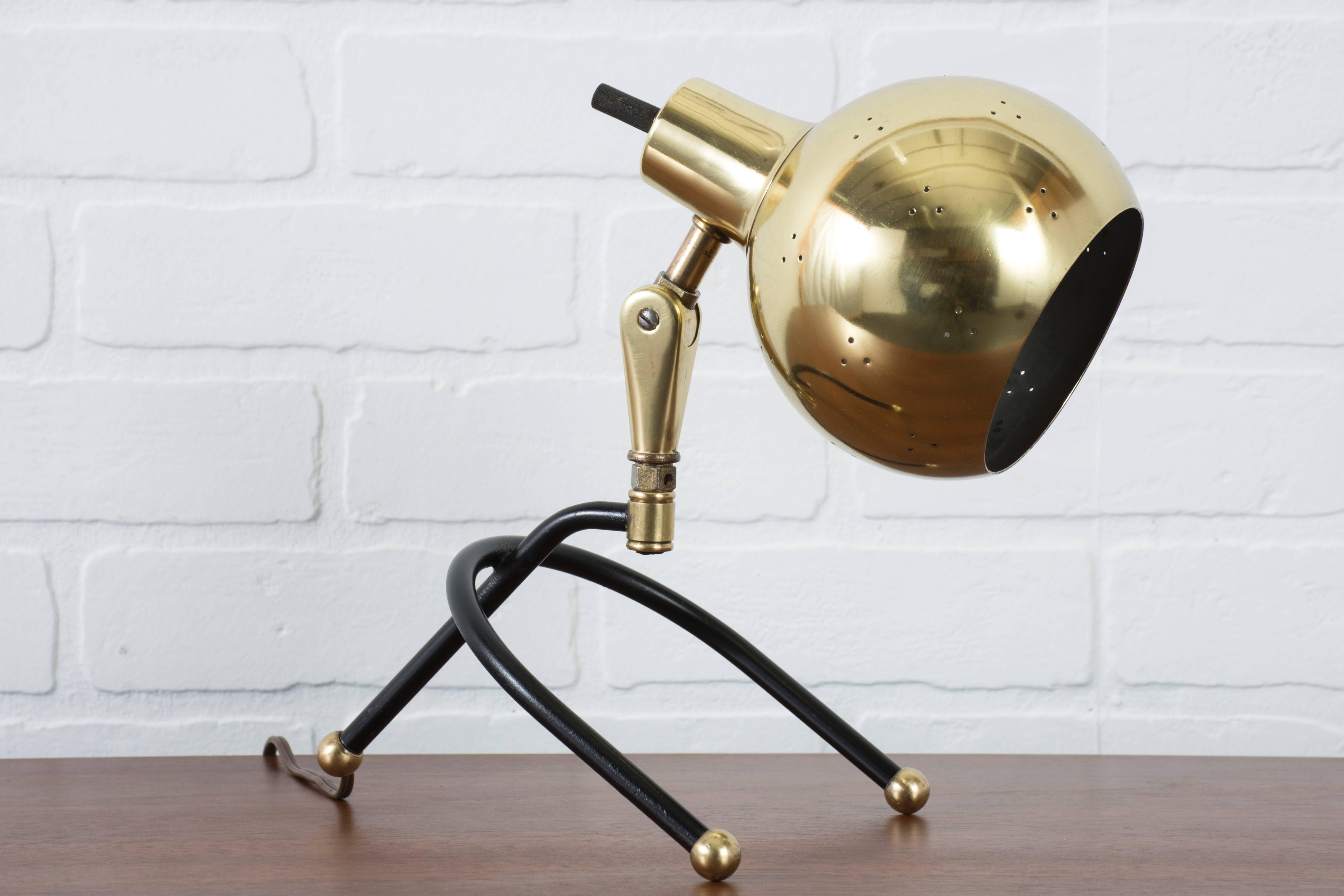 This is a Mid-Century Modern task lamp with a black tripod base and adjustable brass shade.