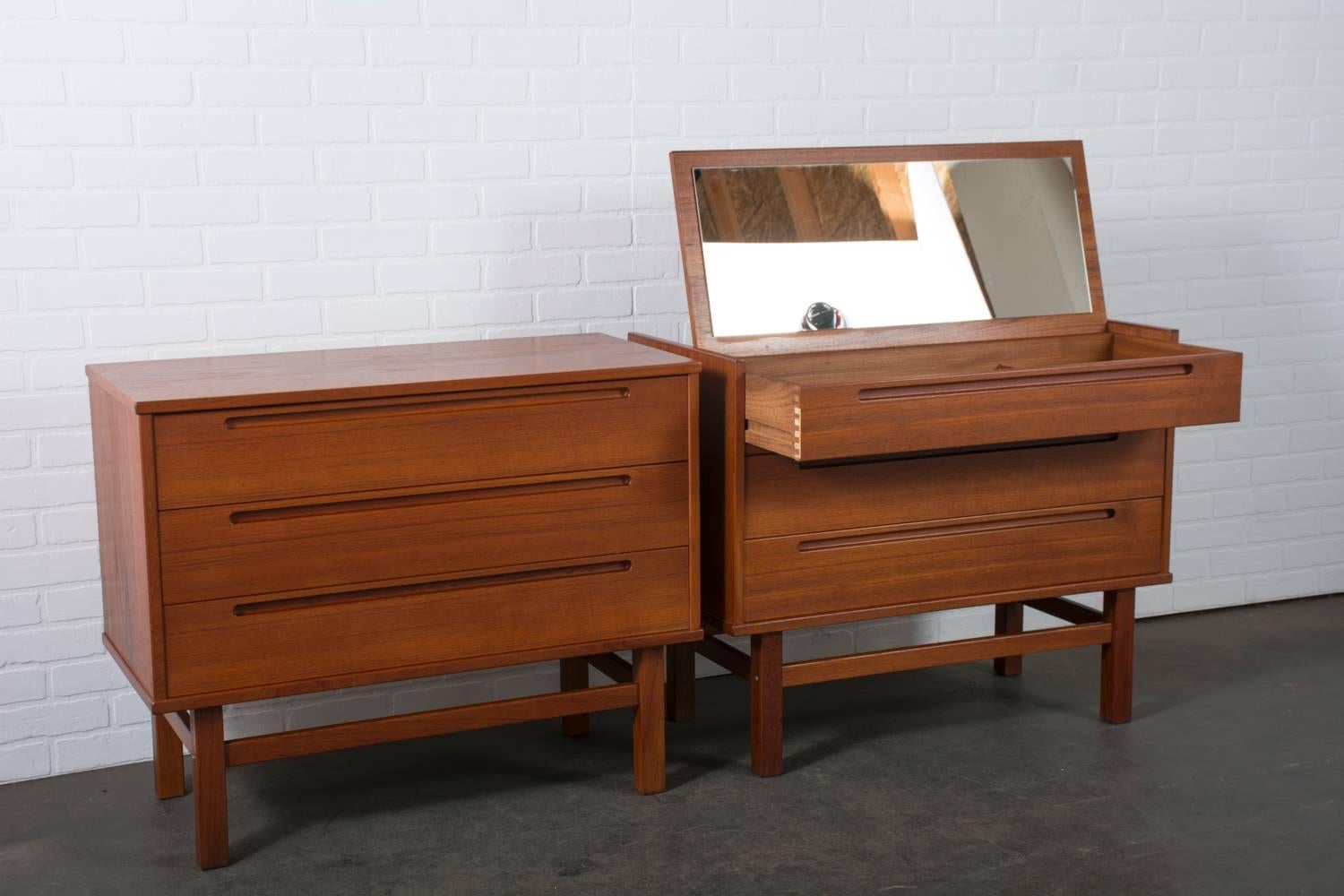 This Danish modern teak dresser and vanity were designed by Nils Jonsson for Torring Mobelfabrik and produced by HJN Mobler, Denmark, circa 1960s. This set features one three drawer dresser and one vanity with two drawers below. What appears to be