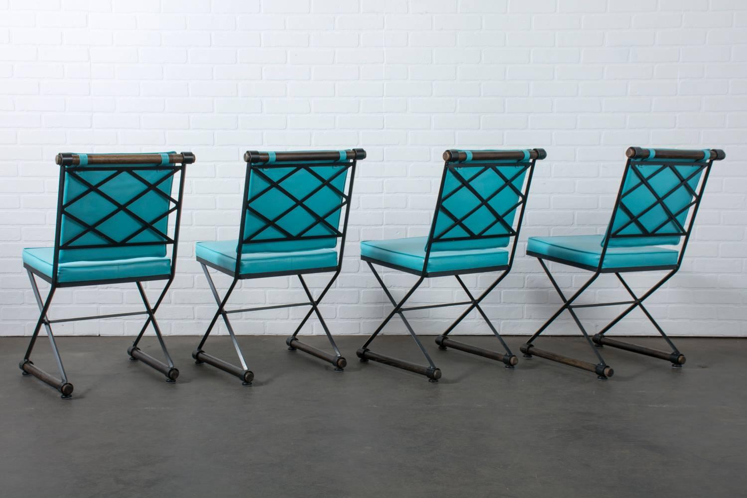 This is a set of four dining chairs that were designed by Cleo Baldon in the 1960s. They feature wrought iron frames, oak stretchers and the original foam and turquoise Naugahyde upholstery. Original glides.