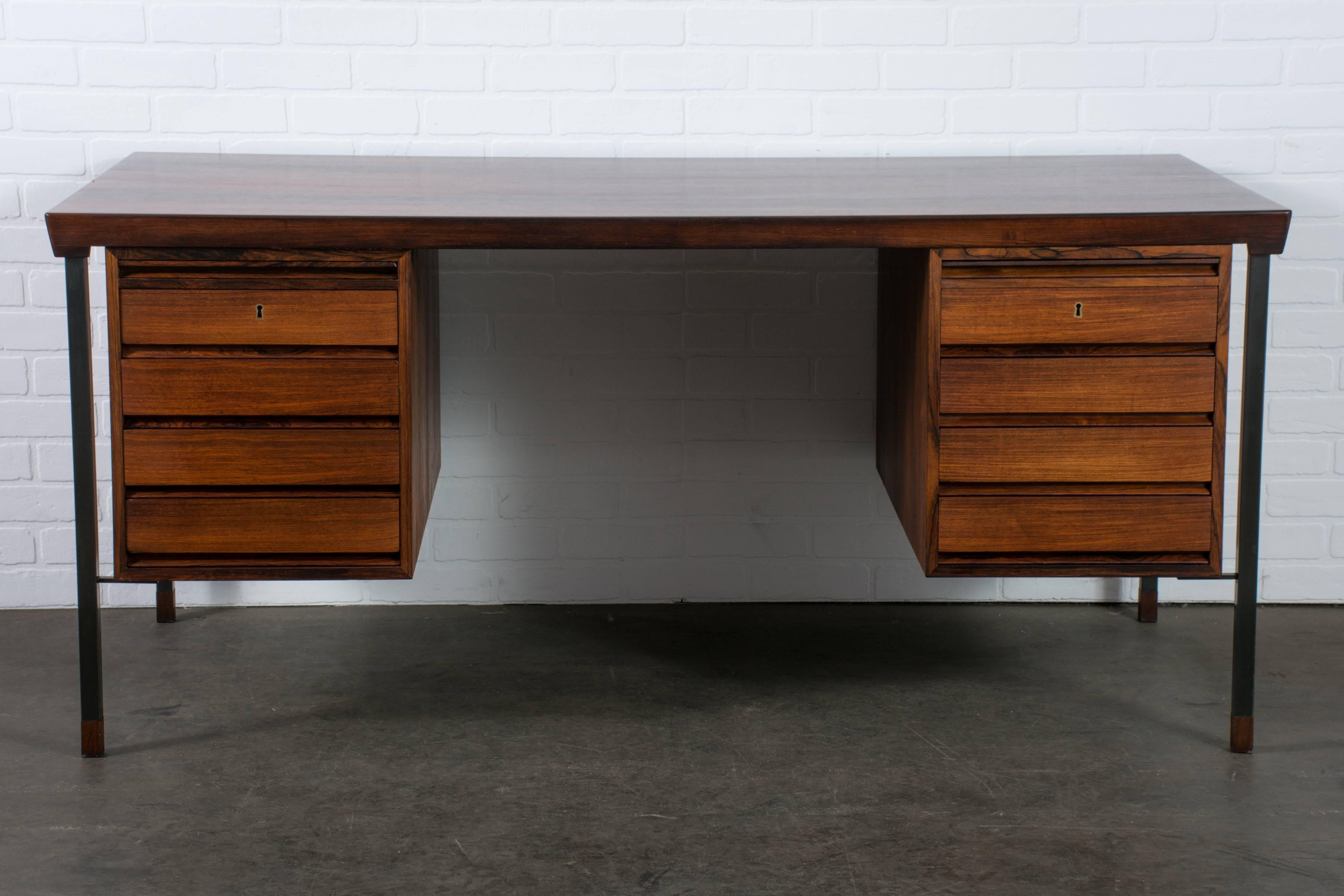 This Danish Modern rosewood desk was designed by Peter Hvidt and Orla Molgaard-Nielsen for Soborg Mobelfabrik in the 1960's, Denmark. It features eight drawers (the top two with small removable trays for pens, etc.) and two trays with glass tops