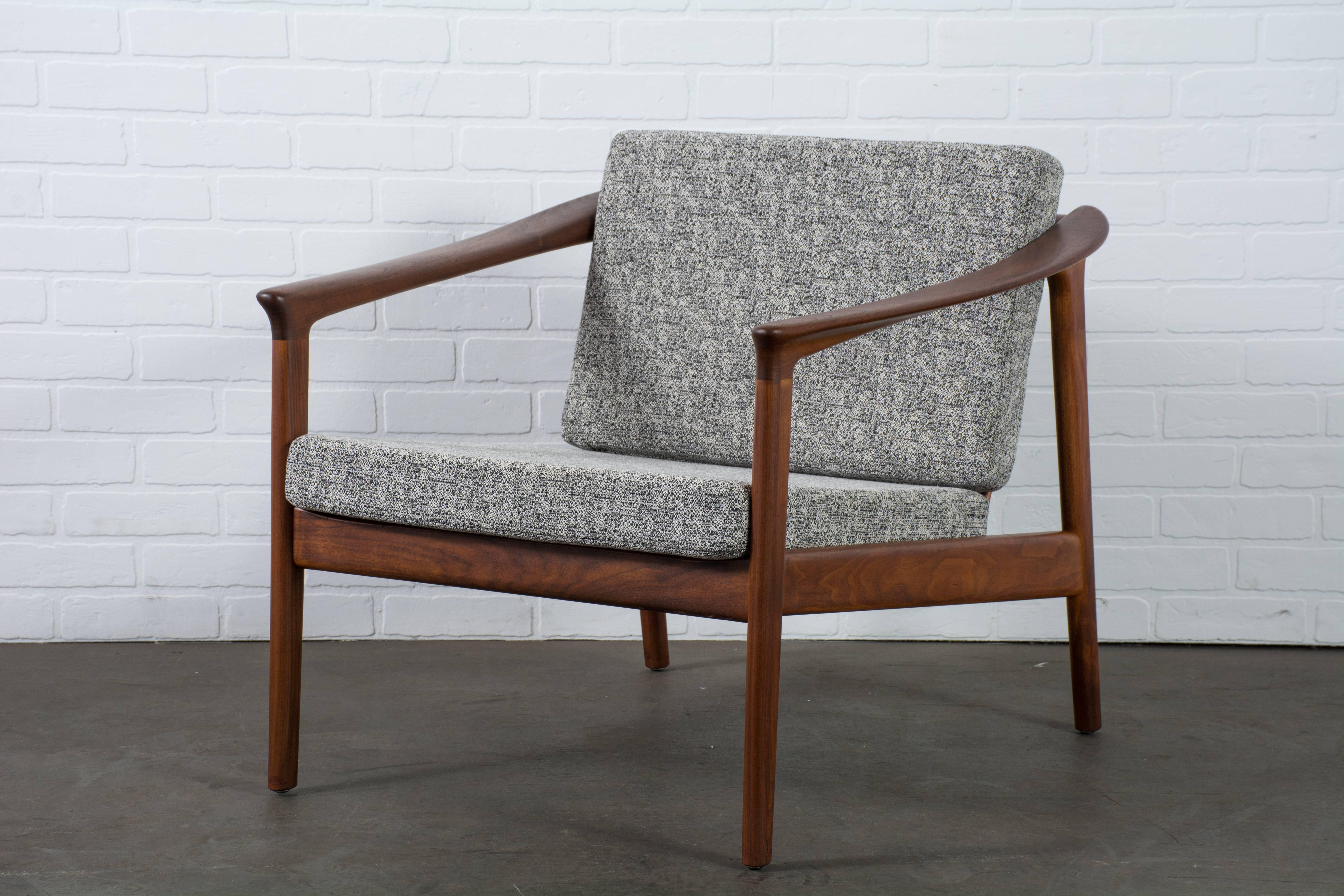 This Scandinavian Modern lounge chair was designed by Folke Ohlsson for DUX in the 1950s. It has a sculptural walnut frame and new cushions that have been upholstered in a black and white fabric. DUX label under the seat.