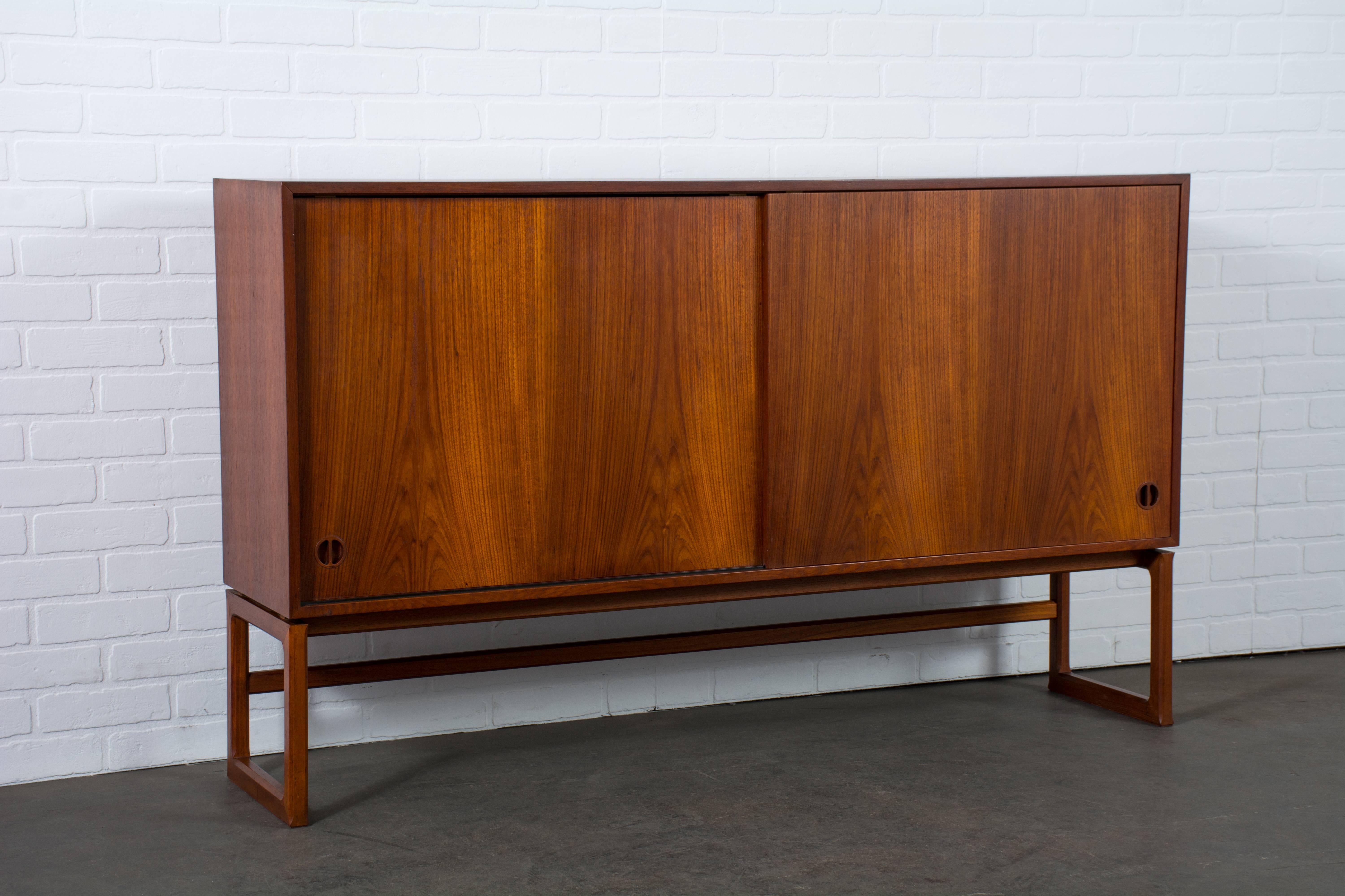 This vintage Mid-Century teak cabinet has two sliding doors that conceal three adjustable shelves. Marked Made in Denmark, Borchorst & Lindhard, 1958.