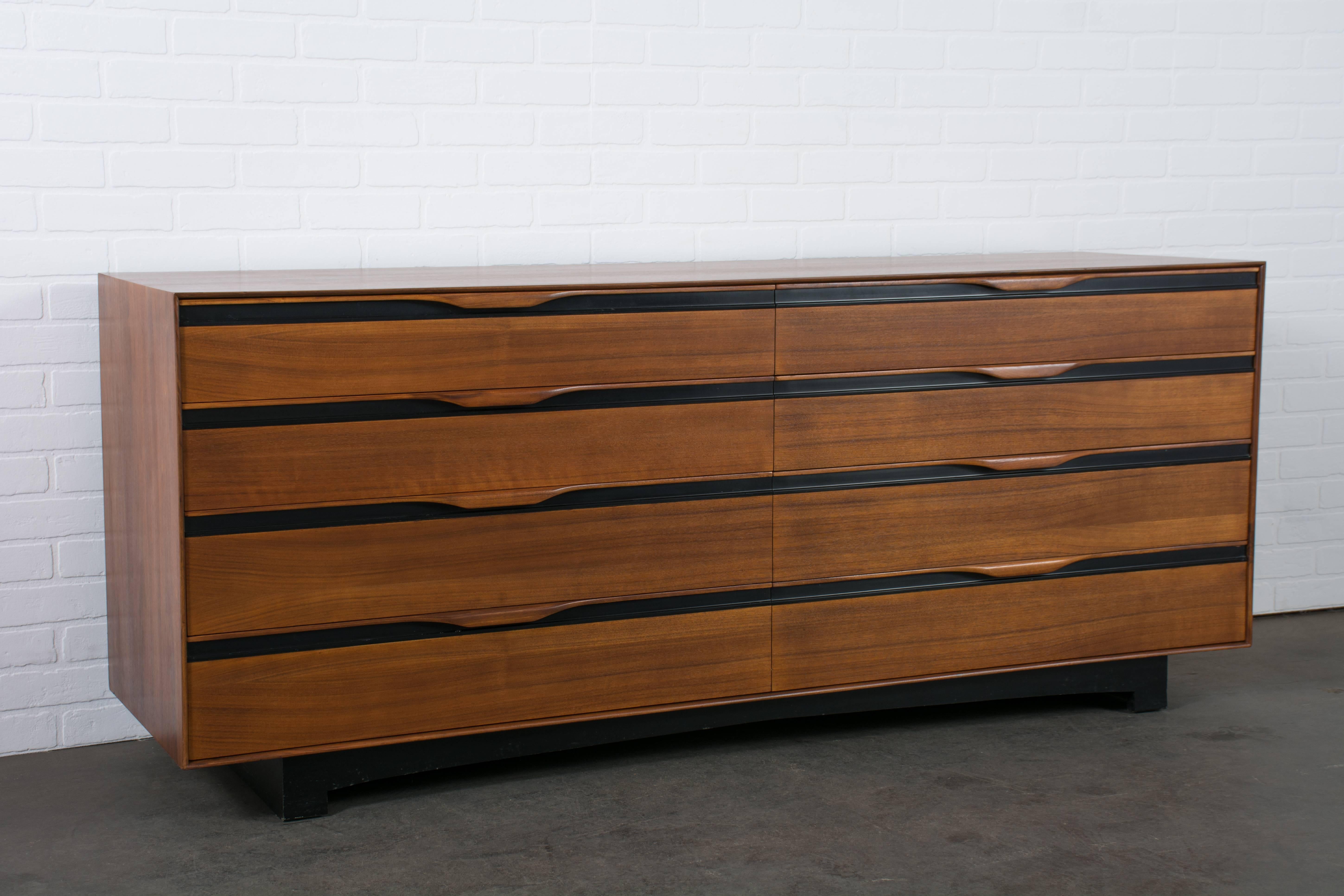 This Mid-Century Modern eight-drawer dresser was designed by John Kapel for Glenn of California in the 1960s. It is walnut with black accents and sculptural handles. Includes many adjustable dividers for the drawers. Matching nightstands available