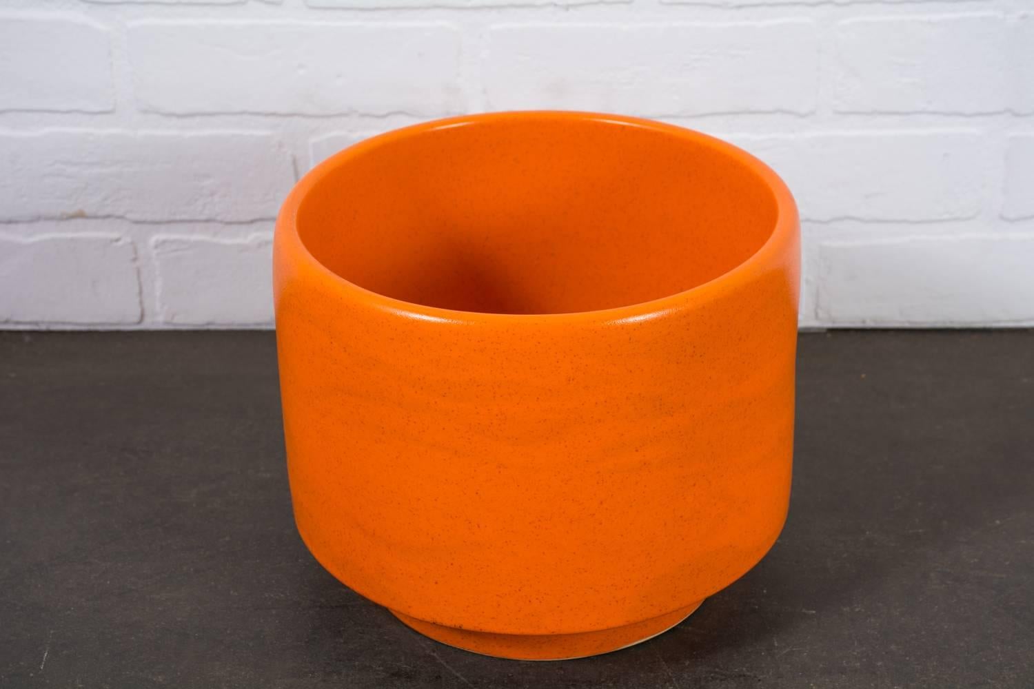 This is a California Modern ceramic pot by Gainey Ceramics, La Verne, California (model C-10). The glaze is bright orange with little dark specs.