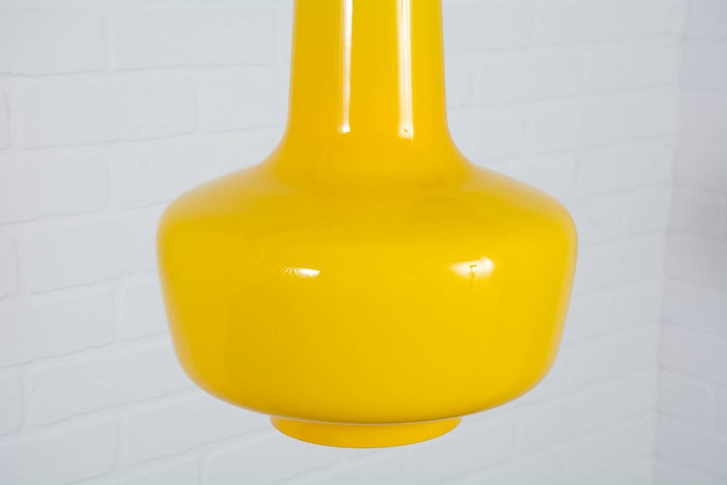 This Danish Modern 'Kreta' hanging lamp was designed by Jacob E. Bang for Fog and Mørup in the 1960s. It was manufactured by Holmegaard Denmark. This vintage Mid-Century pendant lamp has a funnel shape in a vibrant canary yellow. The glass pendant