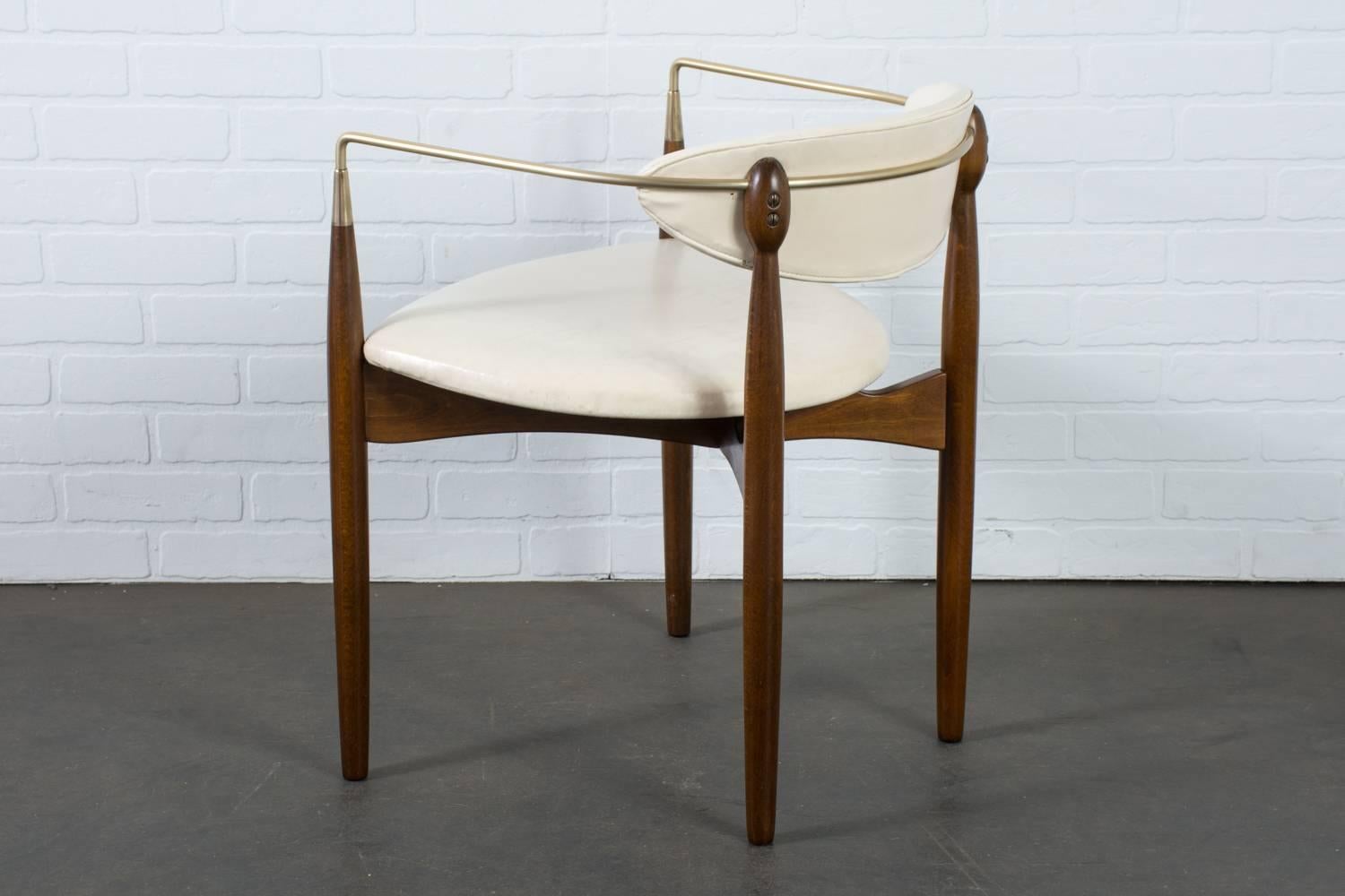 This vintage midcentury 'Viscount' chair was designed by Dan Johnson for Selig, circa 1950s. It features a wood frame with a walnut finish, slender brass tubing that wraps around the back of the backrest and bends attaching to the top of the tapered