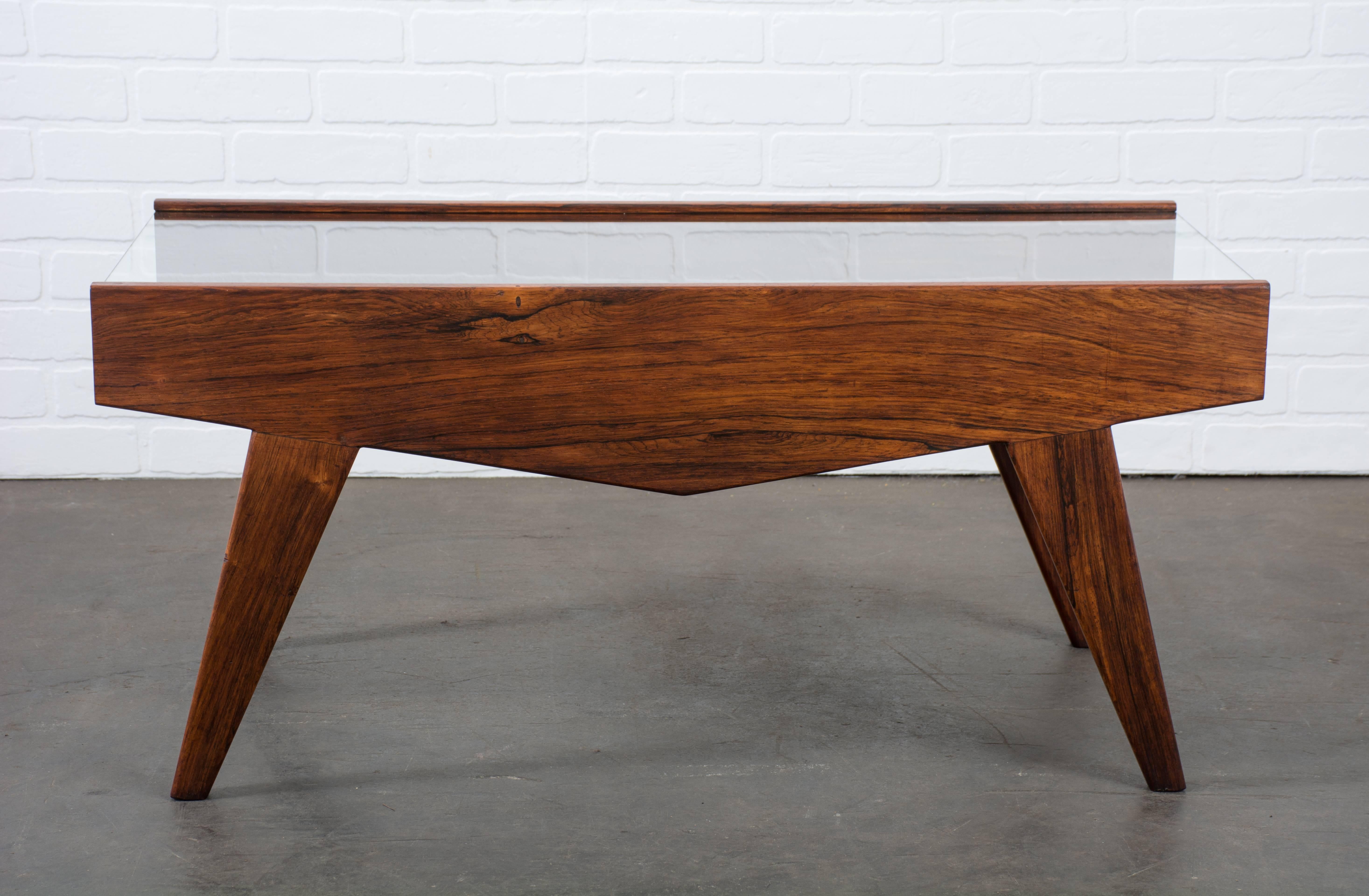 This is a vintage Mid-Century coffee table with a solid Brazilian rosewood base and a new glass top that slides out to reveal a storage space for books and magazines.