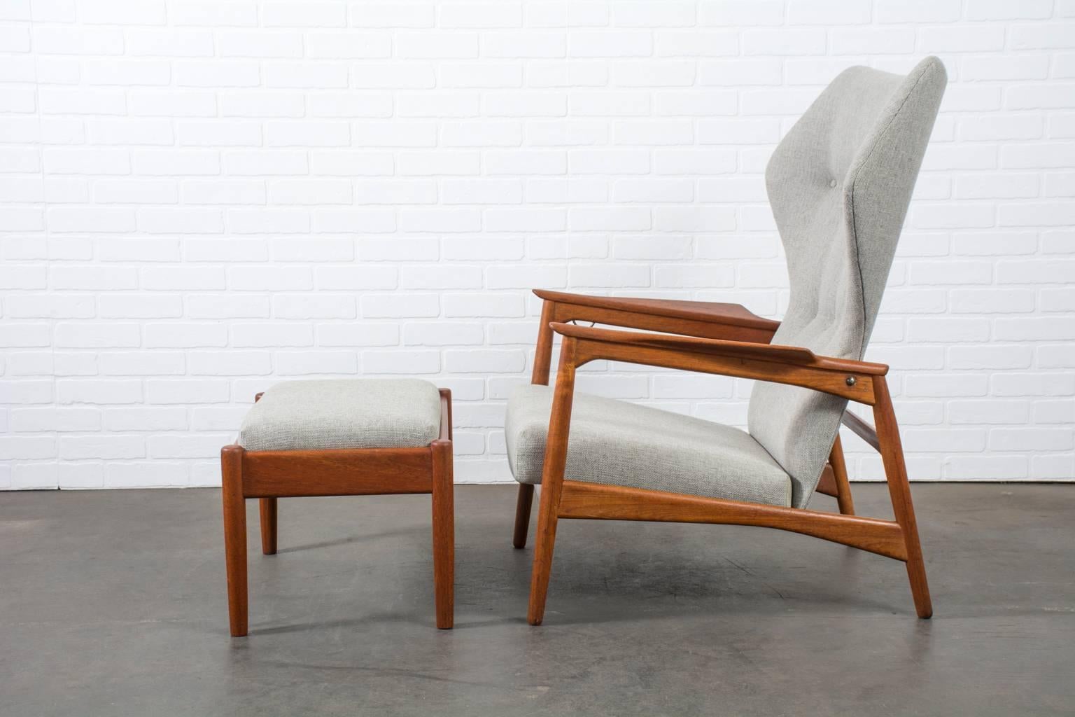 This is a vintage Mid-Century high back lounge chair and ottoman designed by Ib Kofod-Larsen for Carlo Gahrn in 1954. It has a solid teak frame and has been professionally reupholstered in a grey fabric. Can be adjusted in three positions. Beautiful