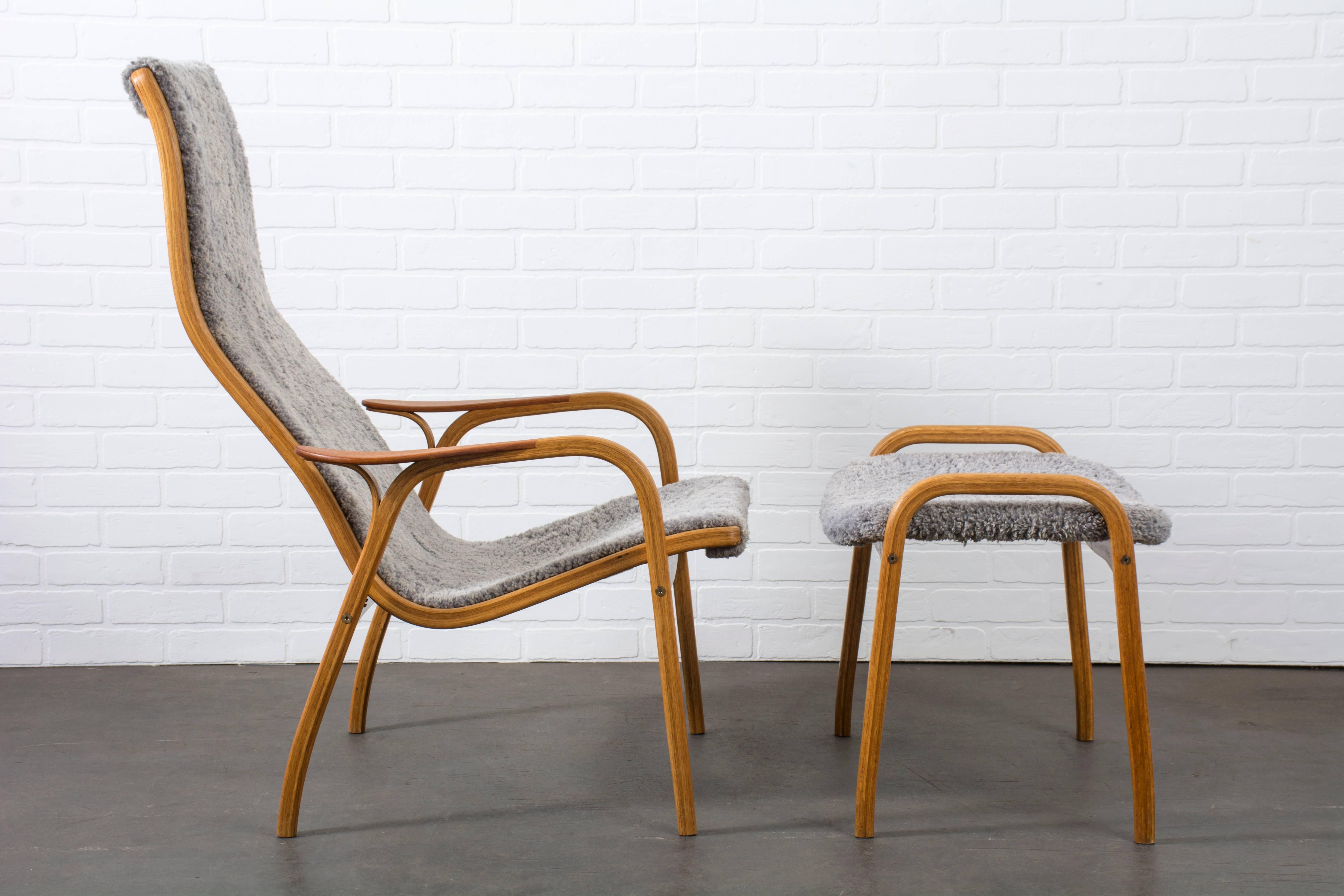 This high back 'Lamino' lounge chair and ottoman was designed by Yngve Ekström for Swedese Mobler in the 1950s. It features a teak frame and the original grey sheepskin upholstery.