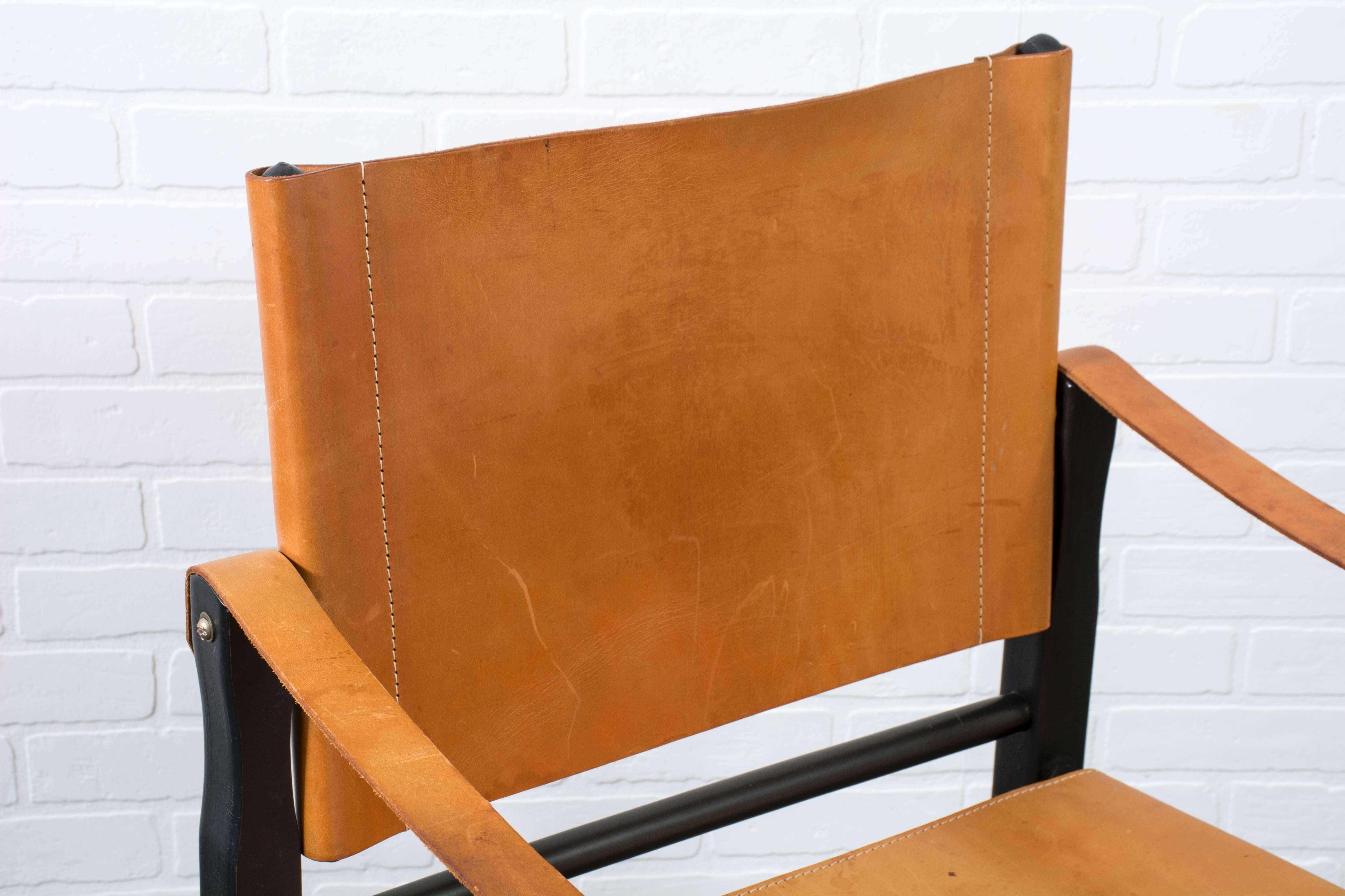This is a vintage Mid-Century leather safari chair with a black frame.
