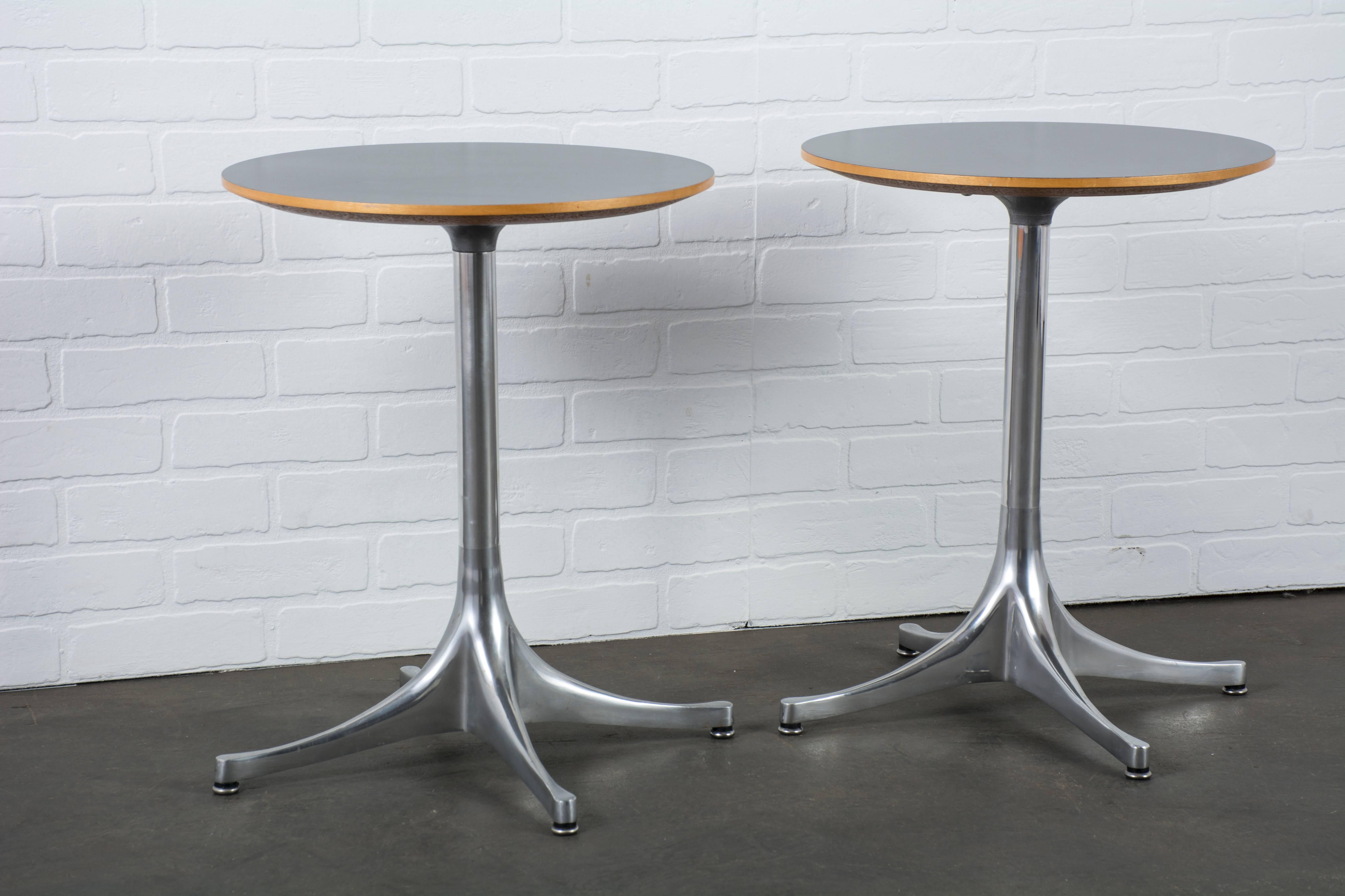 This is a pair of side tables by George Nelson for Herman Miller. The model 5451 end table was designed in 1954 and is still being produced today. They feature polished aluminum bases and black laminate tops with maple veneer edging.
