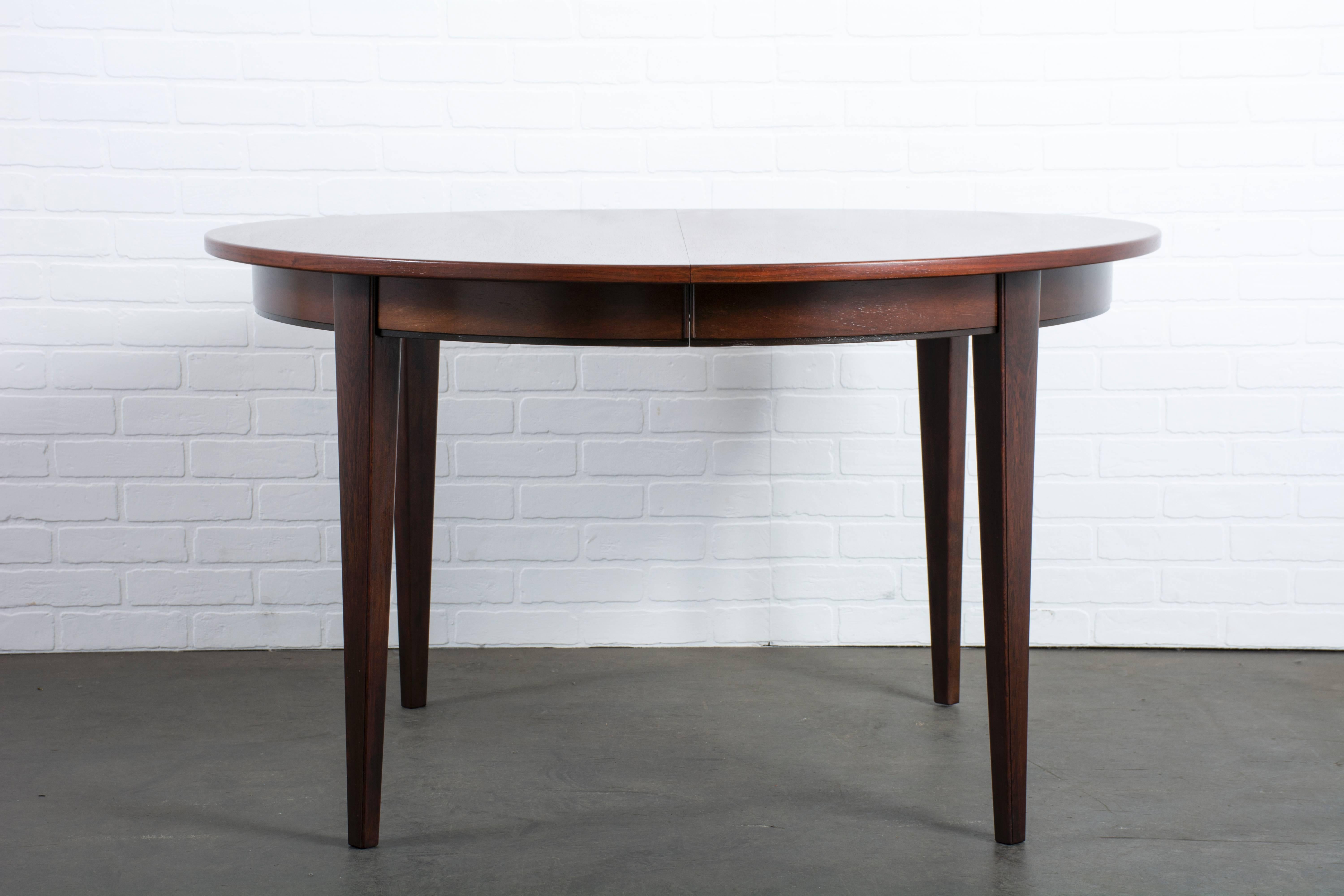 This vintage Mid-Century rosewood dining table was designed by Gunni Omann for Omann Jun in the 1950s, Denmark (Model 55). It can be used round to seat four people or with up to three additional leaves. One of the leaves is rosewood and matches the