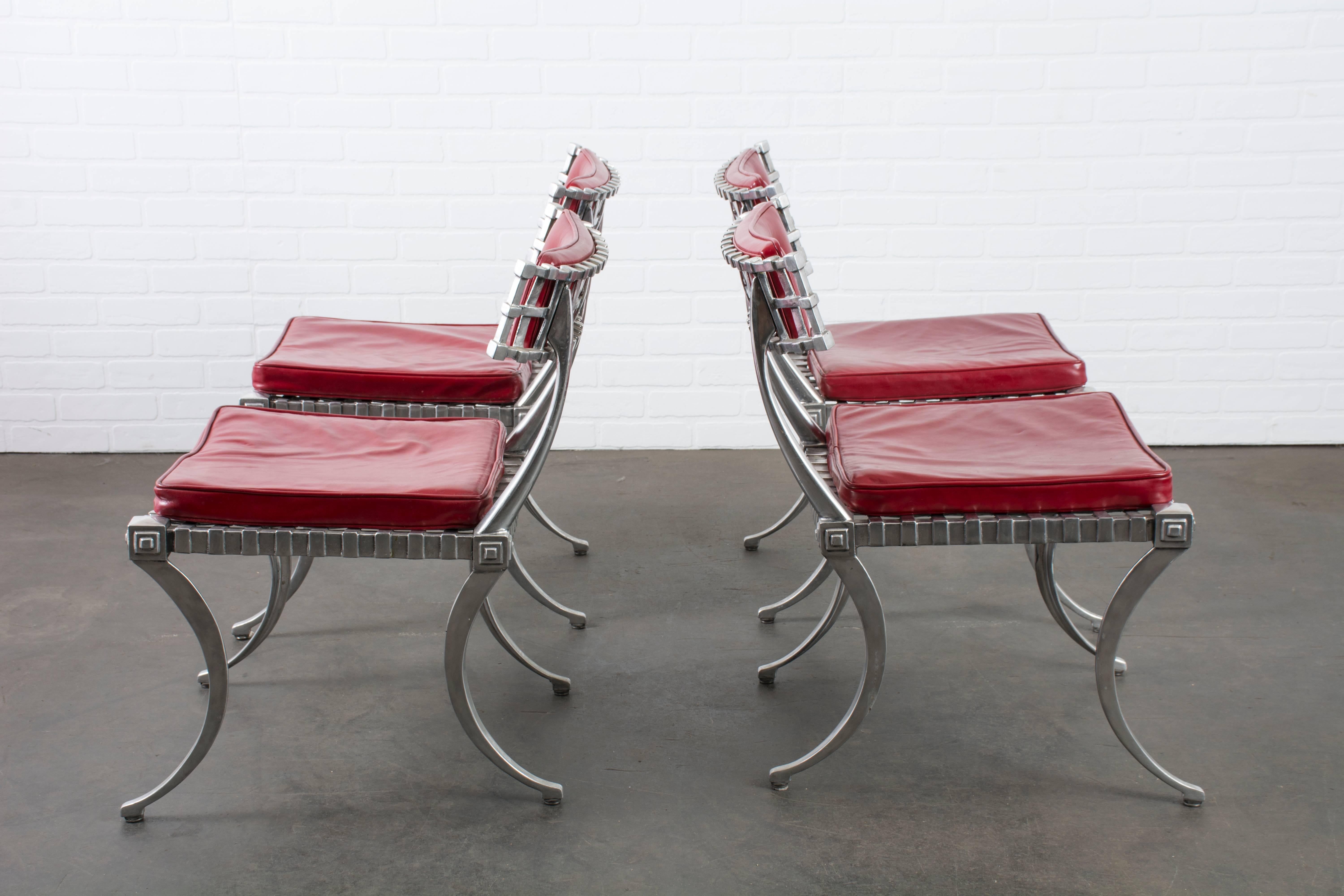 This vintage Klismos dining set by Thinline features a round table and four chairs with polished cast aluminum frames and red leather upholstery. It is marked Thinline, Santa Ana, Calif.

Table: 50.5