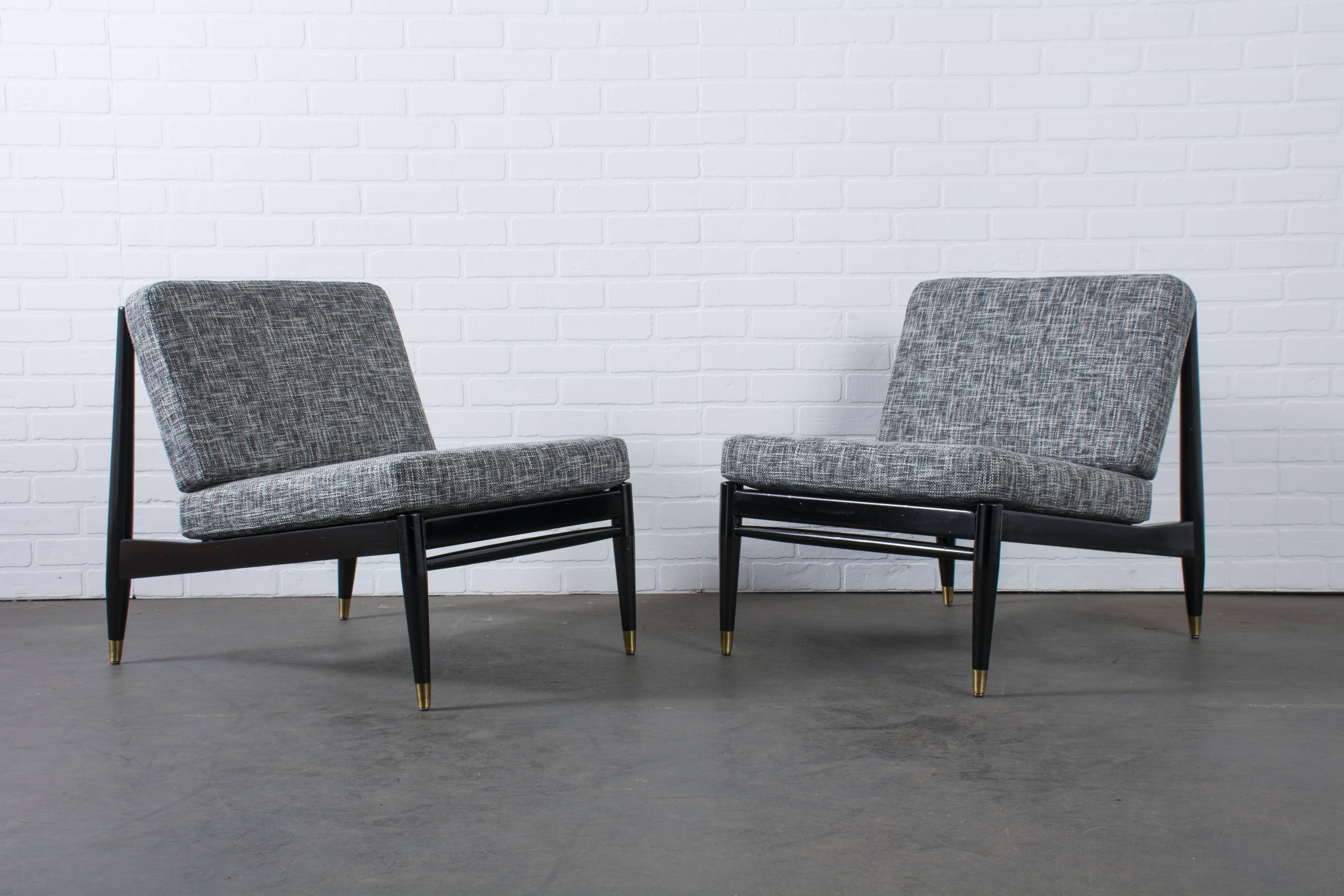 This is a pair of vintage Mid-Century lounge chairs with black frames, gold accents and new black/white upholstery.