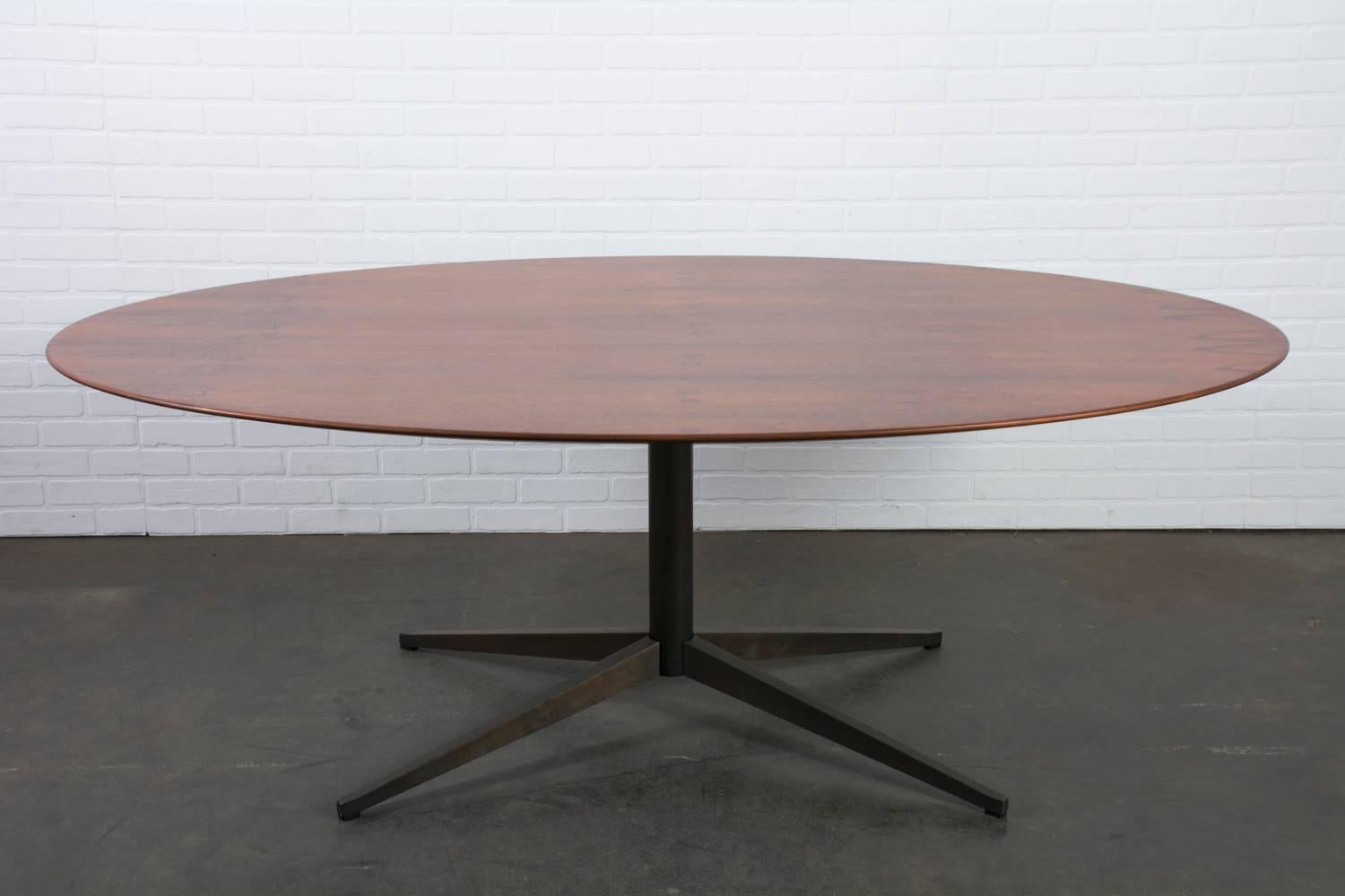 This Mid-Century Modern table was designed by Florence Knoll for Knoll International, USA, circa 1960s. It features a rosewood tabletop and a steel X-shaped base with a bronze finish. This table can be used as a dining table, conference table, or