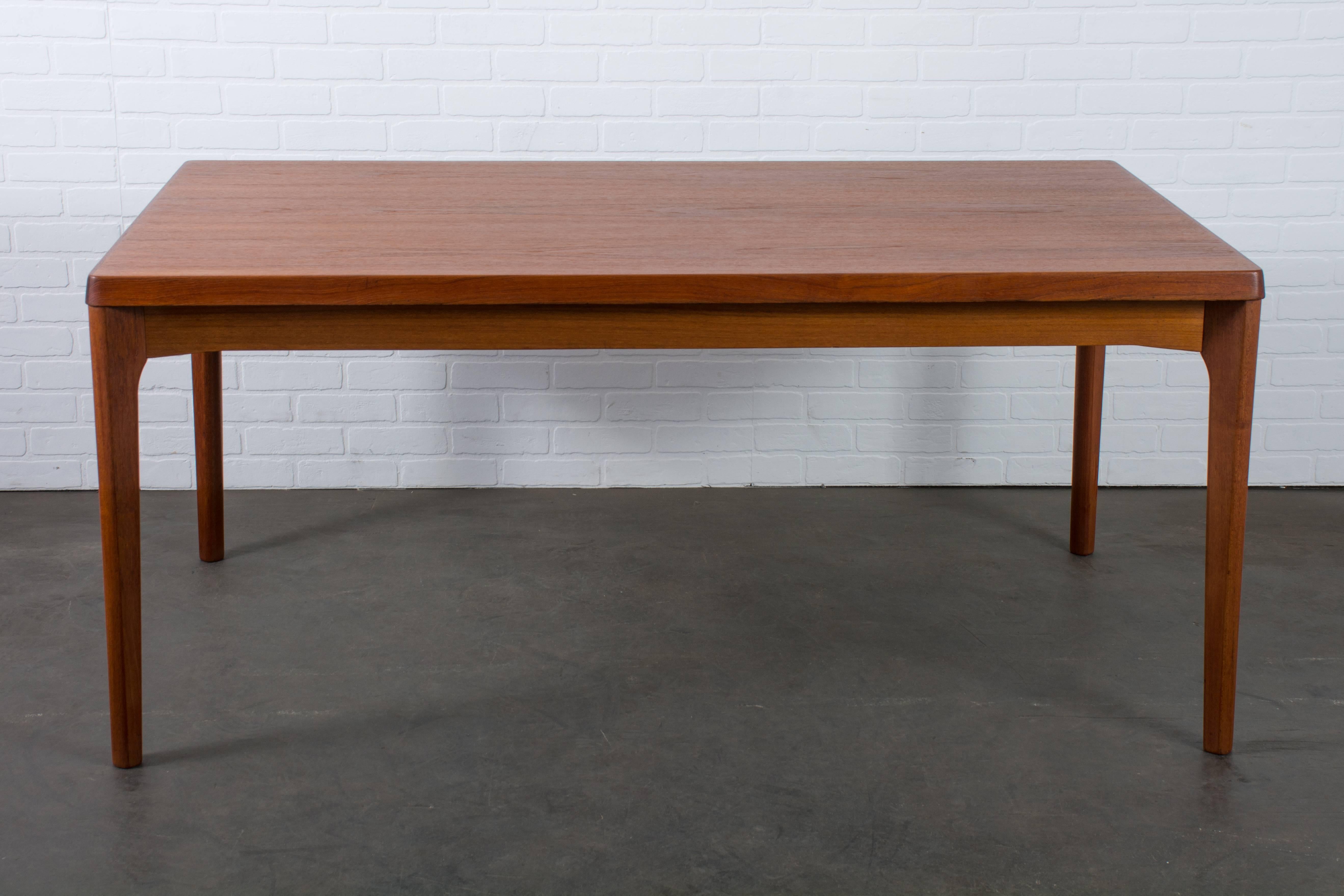 This vintage Mid-Century teak dining table was designed by Henning Kjaernulf for Vejle Stole Mobelfabrik in the 1960s. It features two leaves that can be pulled out to extend the table. They are stored under the table and slide out easily when you