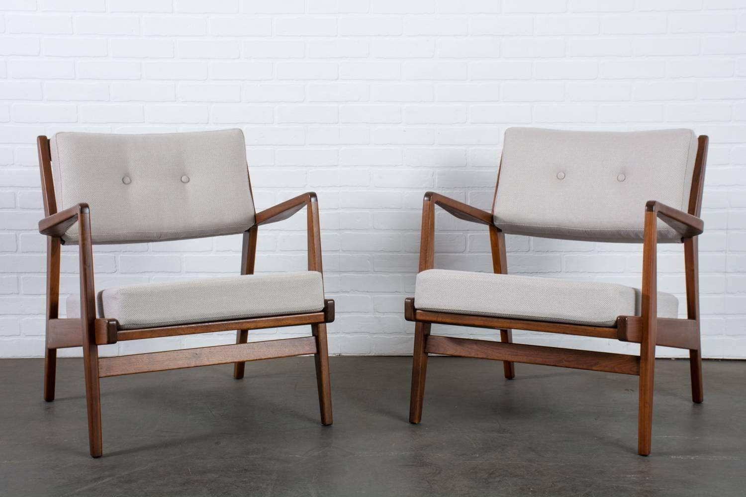 This is a pair of Mid-Century Modern lounge chairs by Jens Risom for Jens Risom Design (model U4230). These vintage chairs have walnut frames and have been professionally reupholstered in a silver grey fabric. Jens Risom label under the seat.