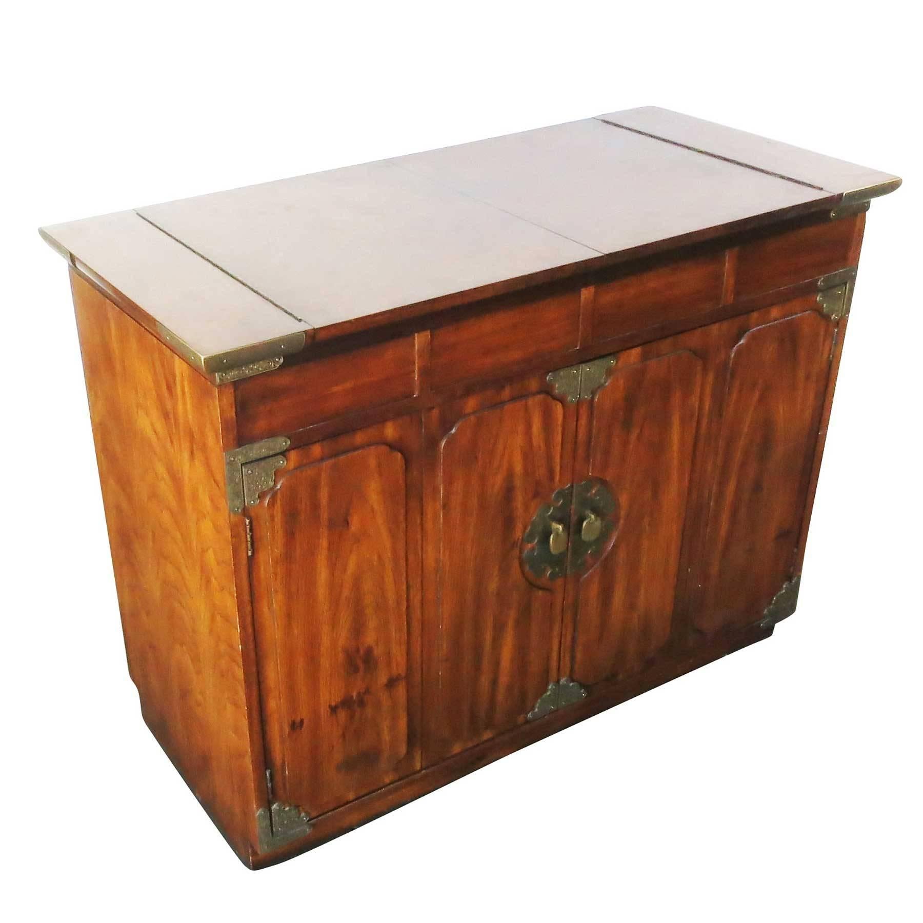 Asian inspired small credenza with two front cabinet doors complete with brass pulls and accents. This cabinet comes with a unique flip-top with leather topped side folding table top. 

This set designed by Thomasville for Huntley.

  