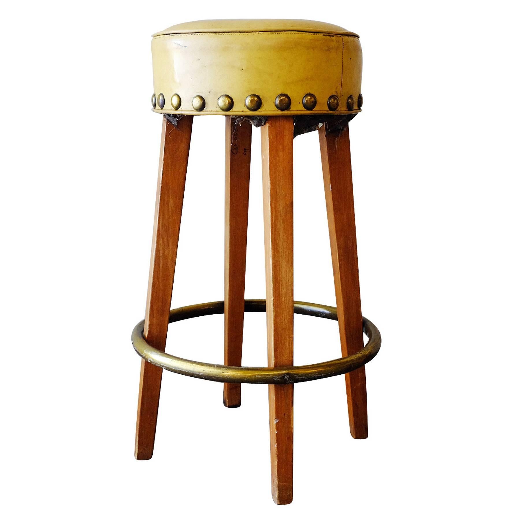 Set of three vintage hand made custom-made mid-century bar stool made from tapered oak legs with a round brass footrest that connect to a yellow vinyl seat. The seat has wraparound oversized nail-head accents.

 
