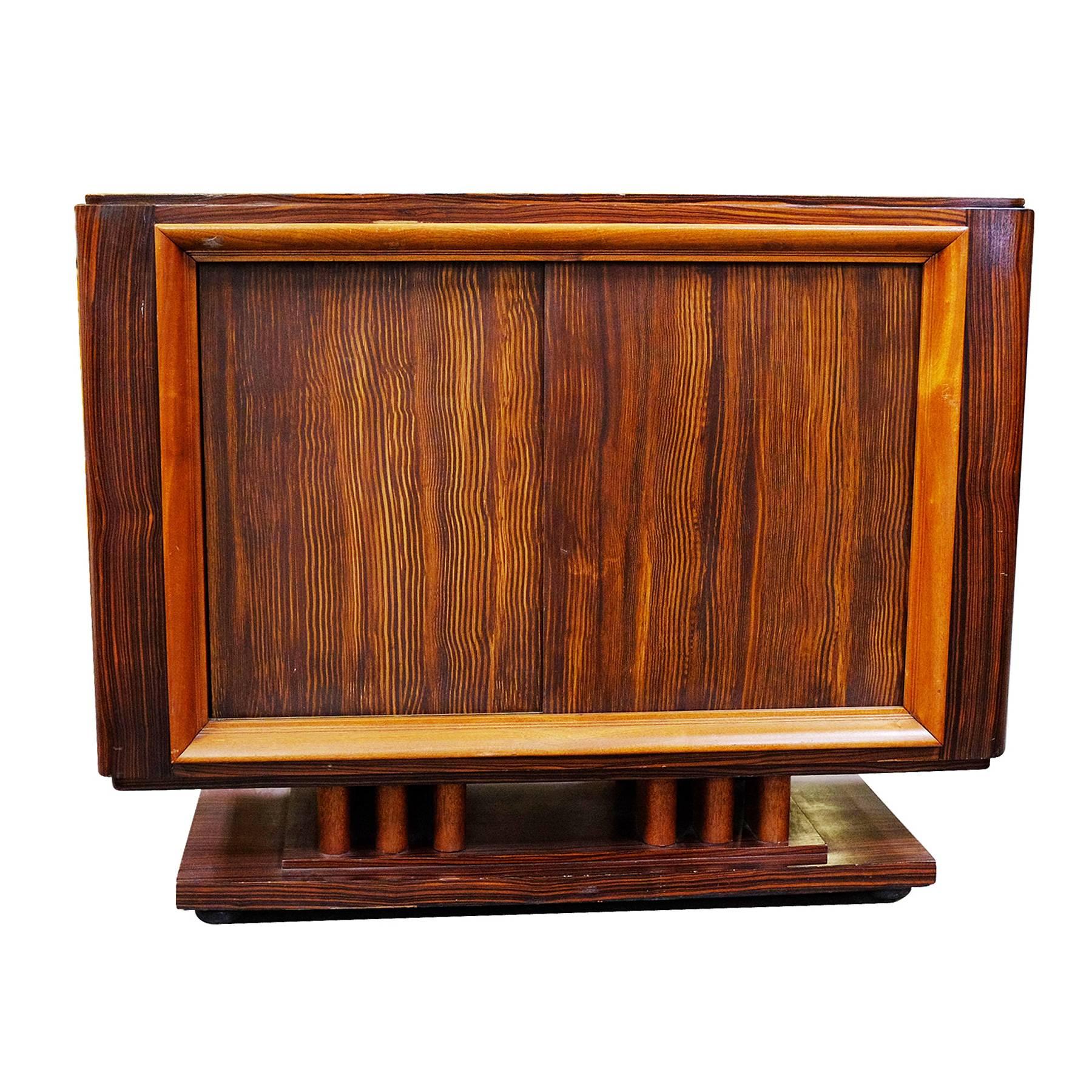 Rare Geometric Art Deco credenza with a dark stained Macassar veneer and two combed wood siding doors opening to a storage space. On the interior you will find bright maple wood lining with adjustable selving. 

The exterior has great early