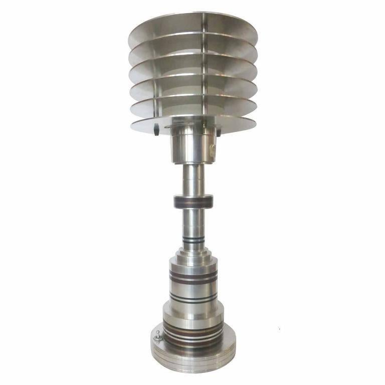 This classic Art Deco machine age style table lamp in the manner of Walter Von Nessen is precise finely crafted hand-built lamp.

The lamp features tiered aluminum with inset bands of brass and bakelite and a center inset socket surrounded by six