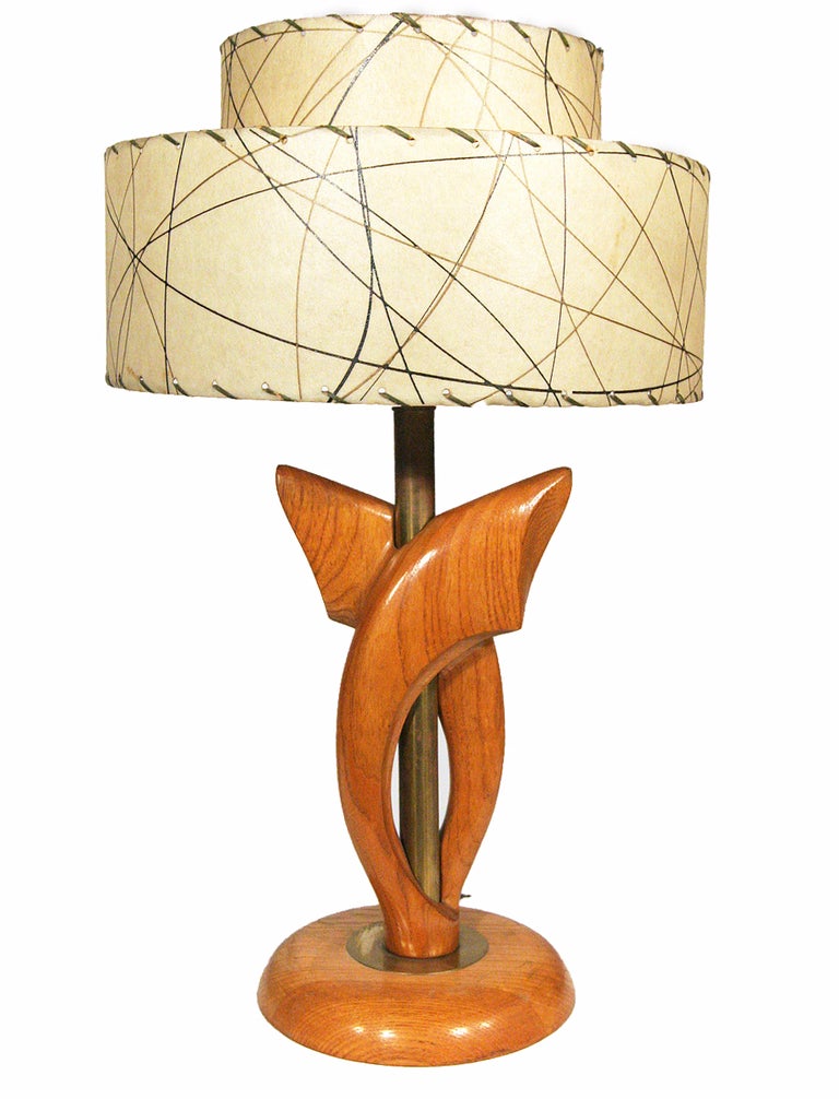 Cette paire de lampes de table conçue par Yasha Heifetz présente des formes sculpturales en chêne enveloppant leurs supports cylindriques en laiton. Les lampes sont dotées d'abat-jour à deux niveaux en point fouet et reposent sur des bases bombées