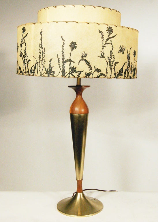 This pair of Mid-Century Modern table lamps features a delicate sculpted form composed of mahogany and brass with brass accents.
The lamps are enhanced by their original two-tier, whip-stitch shades. Mid-Century Mahogany and brass table lamps.