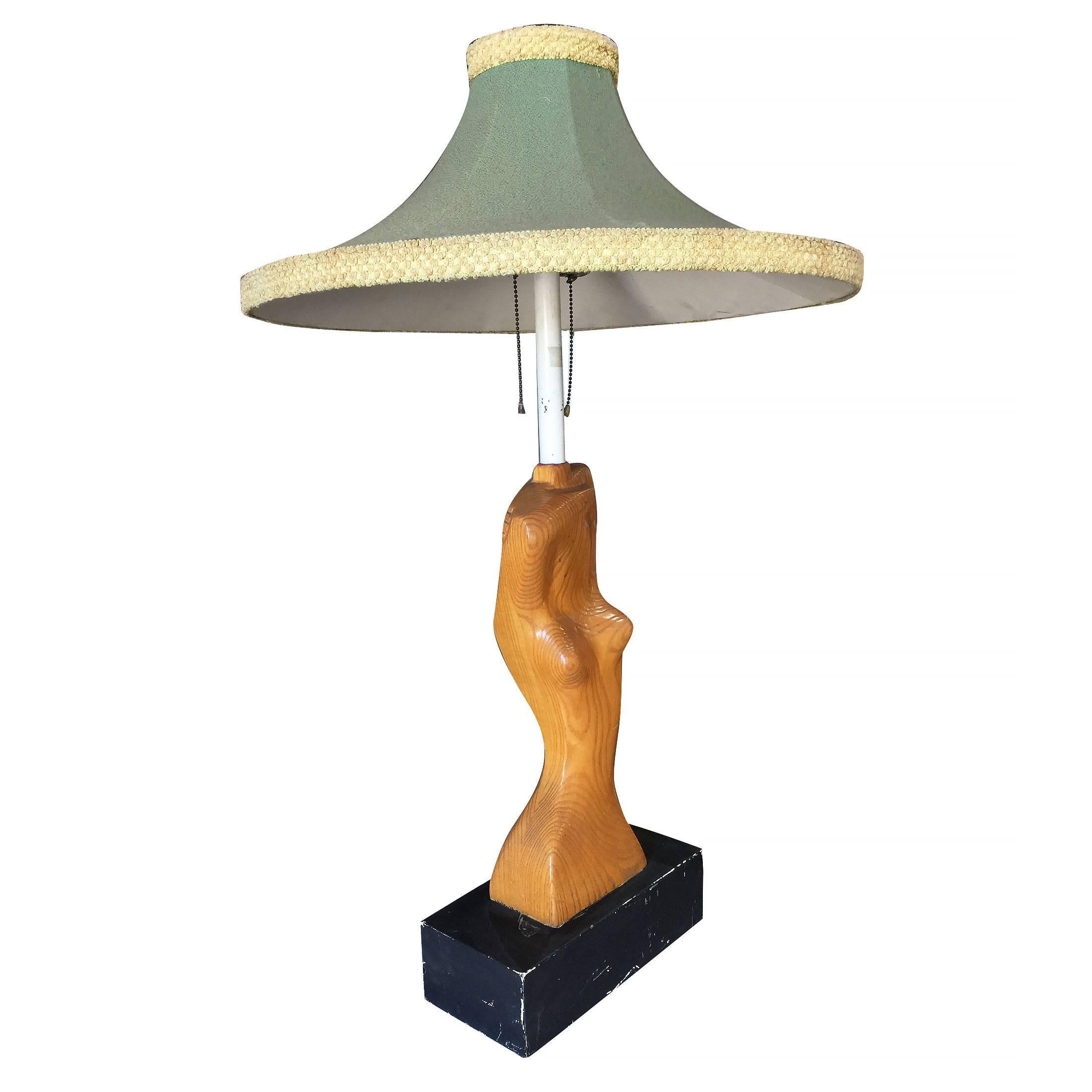 Heifetz style hand carved table lamp featuring an abstract nude female bust resting on a black base. This comes with an original green midcentury shade.