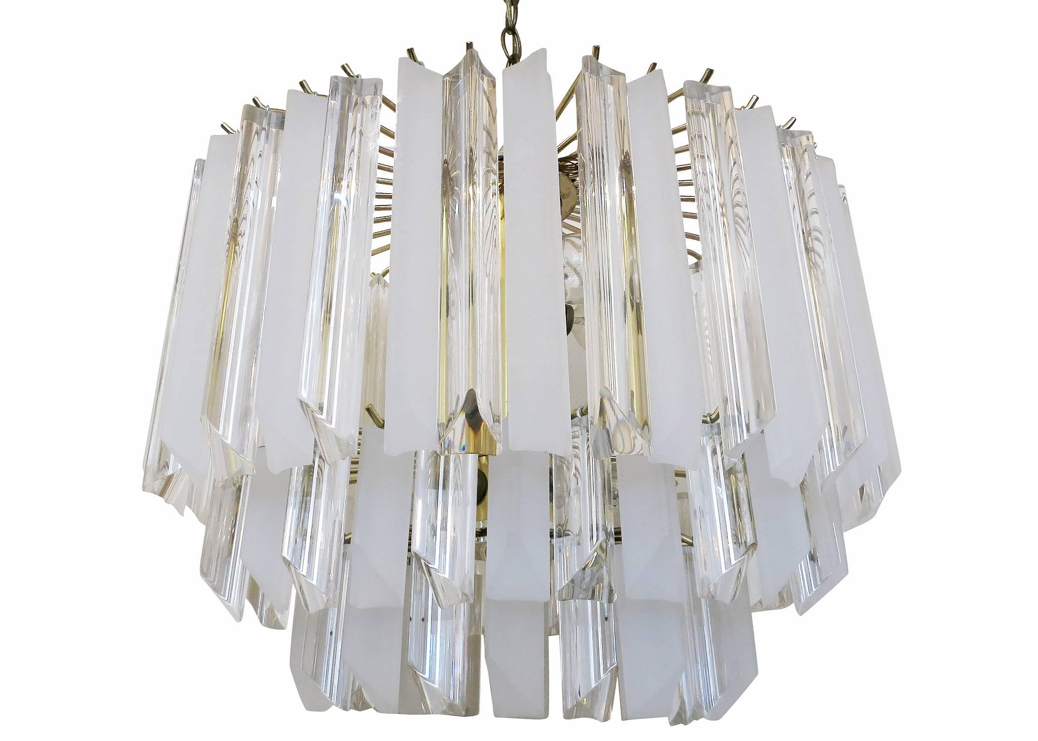 Large circa 1960 Mid Century sculptural lucite prism Chandelier. Comprised of three rows of over 75 triangular lucite prisms of various size which stack inward all hanging from a brass frame.

Features a beautiful two tone pattern of clear and