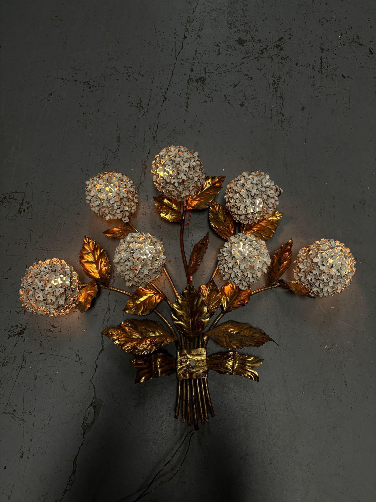 Hand-formed steel and brass Hydrangea floral wall art sculpture and wall sconce. The sculpture lights up from every white enameled steel shade featuring a hinge for easy light bulb replacement and is fixed to brass stems that connect to a brass