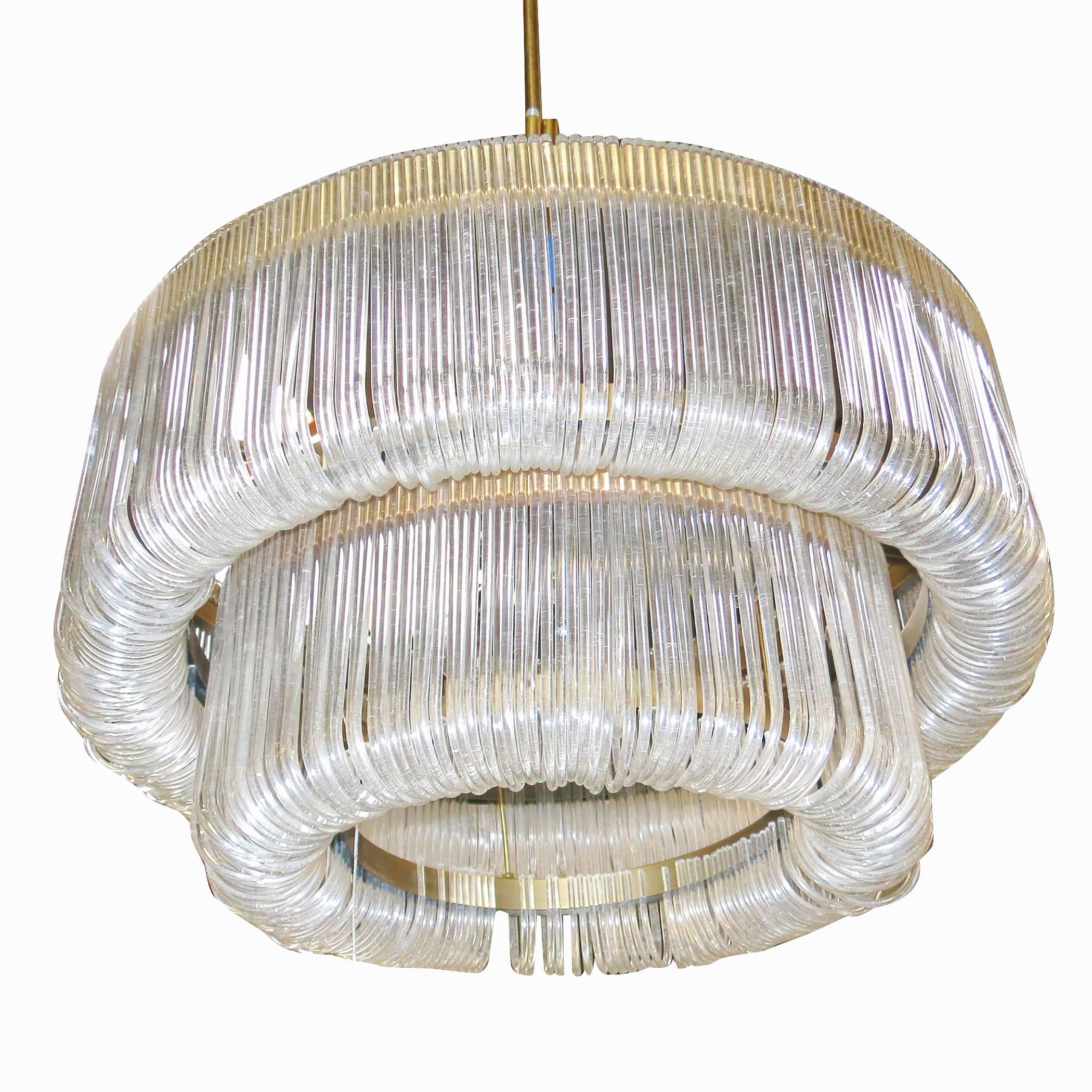 Grand Mid-Century Lucite chandelier. Comprised of hundreds shaped Lucite pieces hanging for a two tier brass frame. This unique chandelier gives an almost prism quality when light up and has a Classic hallmarks of traditional beauty with a very