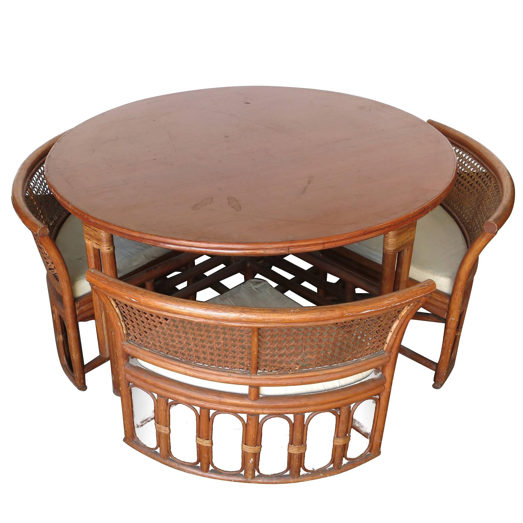 Unique rattan and wickers dining table with four hidden chairs. The chairs feature dark stained rattan frames with wicker seat backs and easily hide away underneath the table. The table uniquely raises up and down from 20