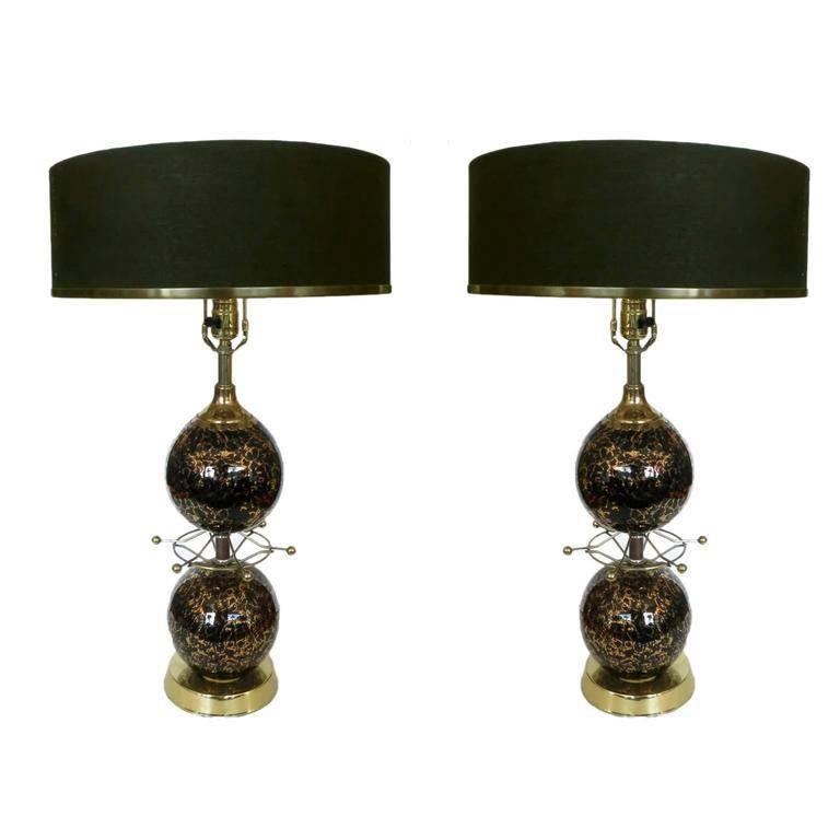 Large gold foil art table lamps with brass starburst detail and black drum shade.

Each lamp features two pieces of black onyx Italian Murano glass with gold foil  fixed to a brass base plate and center pole. Separating the two orbs of glass is a