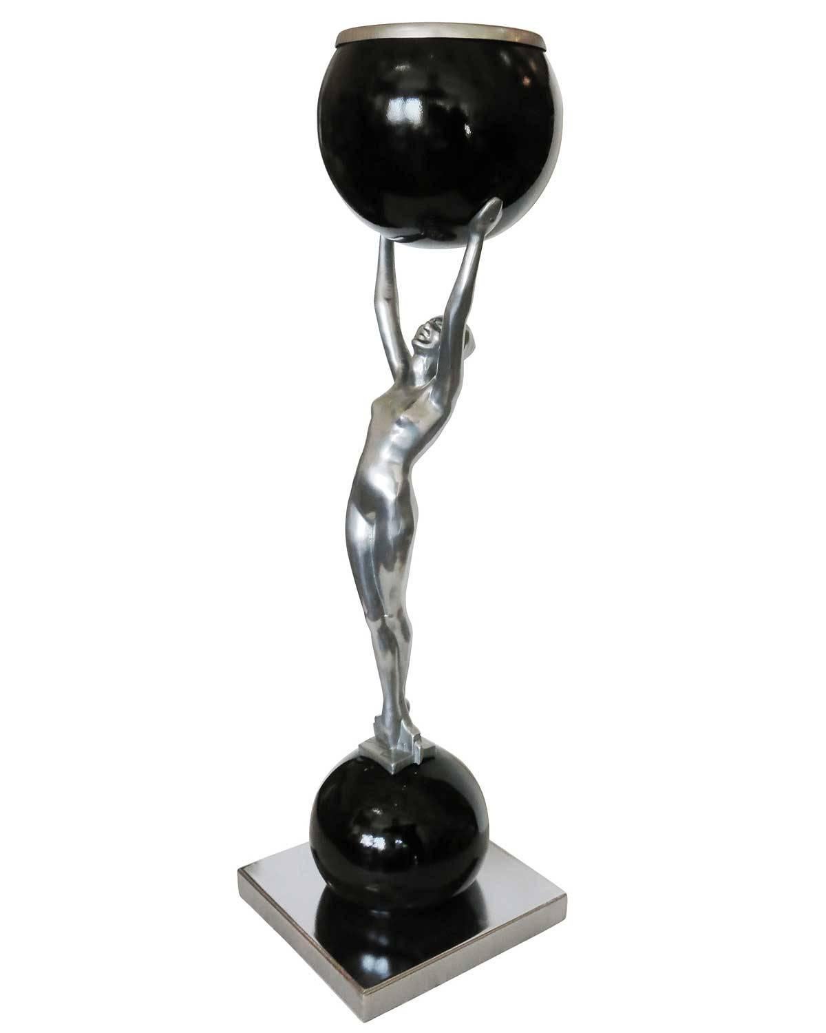Frankart-style table lamp featuring a nude female figure standing on top of a chrome ball holding a black onyx ball that contains a light. 

Available two.