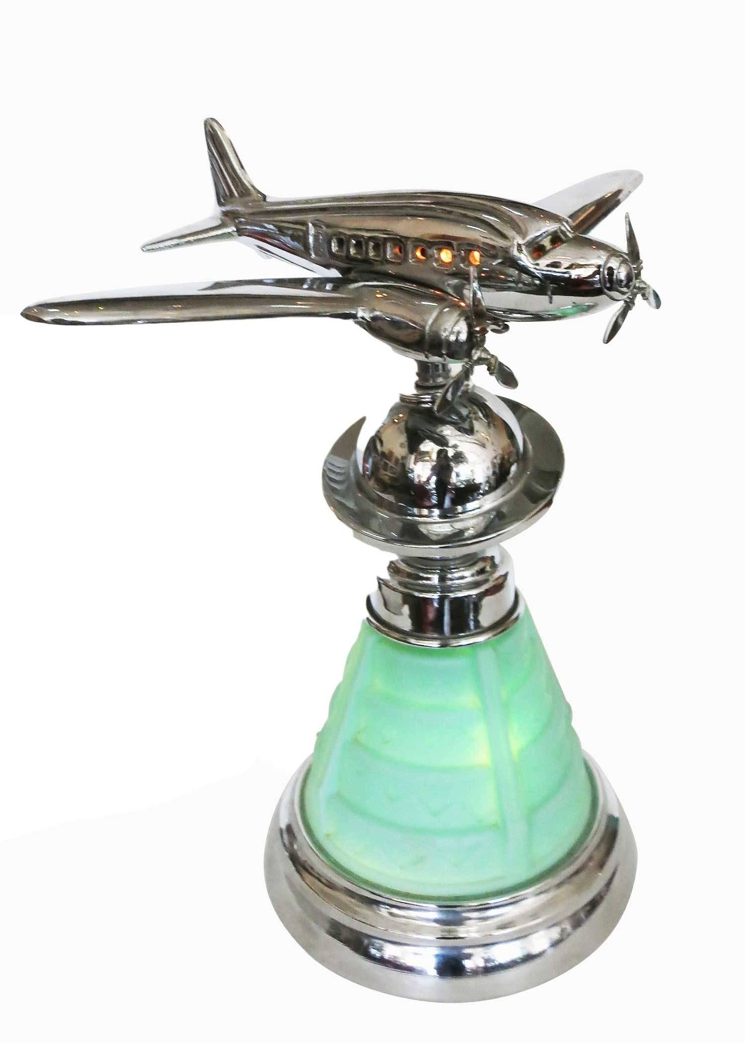 Custom chrome Douglas DC-2 airplane accent lamp, circa 1980. This lamp features a stepped Art Deco style light up green glass base with a chromed Saturn accent neck connecting to a chrome Douglas DC-2 airplane model that lights up.
    
    