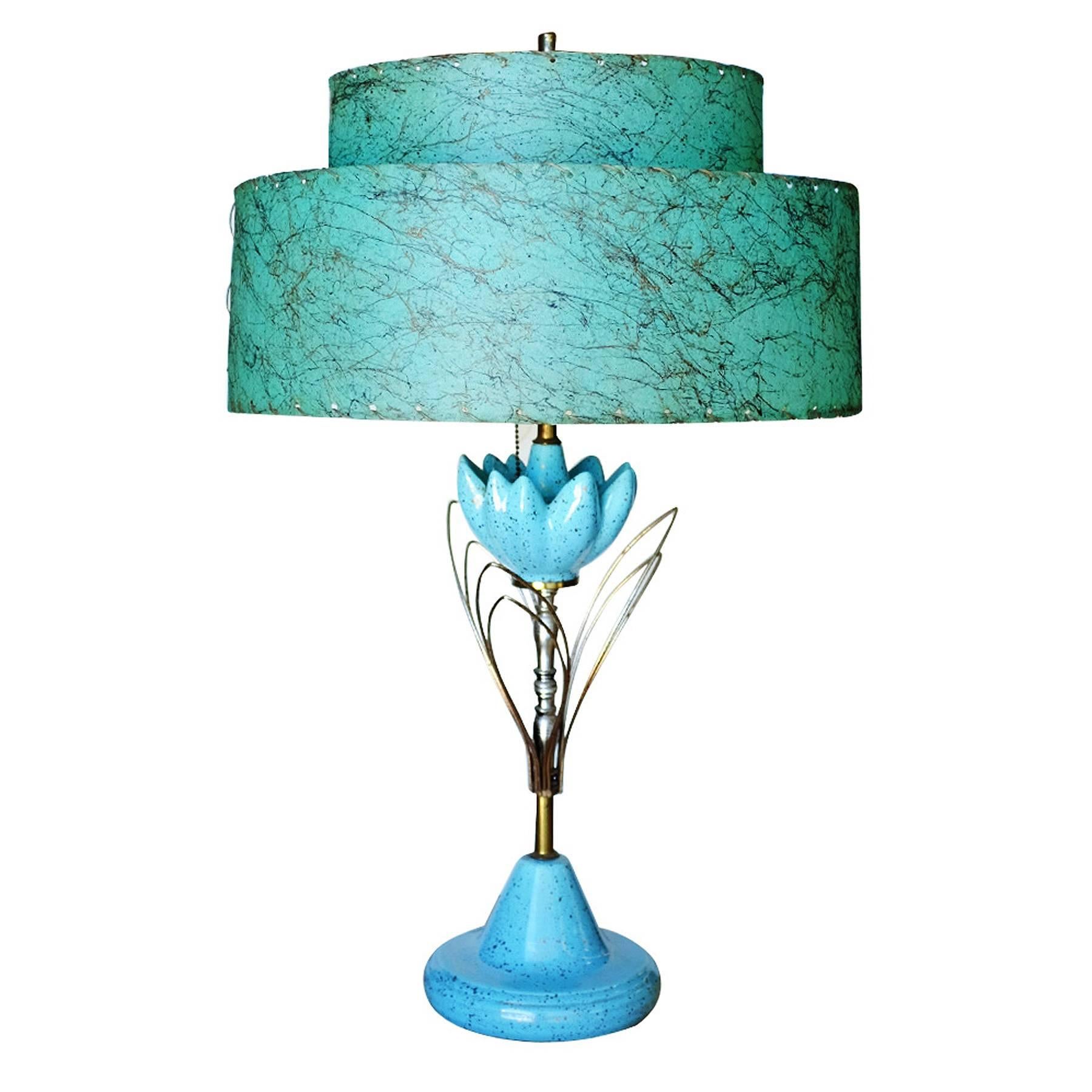 Vintage Mid-Century ceramic sculptural lotus table lamp with original fiberglass whip-stitch shade.

This unique lamp features a ceramic base with a brass stem that branches out to abstract leaves and a ceramic cluster of flower pedals and crowned