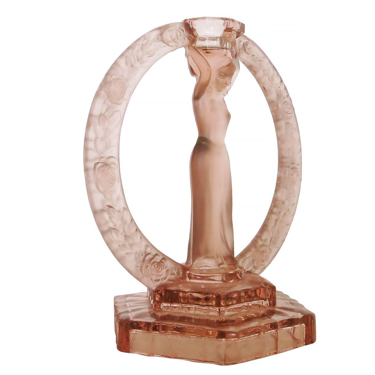 German made Art Deco frosted pink glass Flapper candlestick made

This candlestick features a young Flapper girl standing on a stepped Art Deco base with a floral halo surrounding her holding a candleholder in her hands.