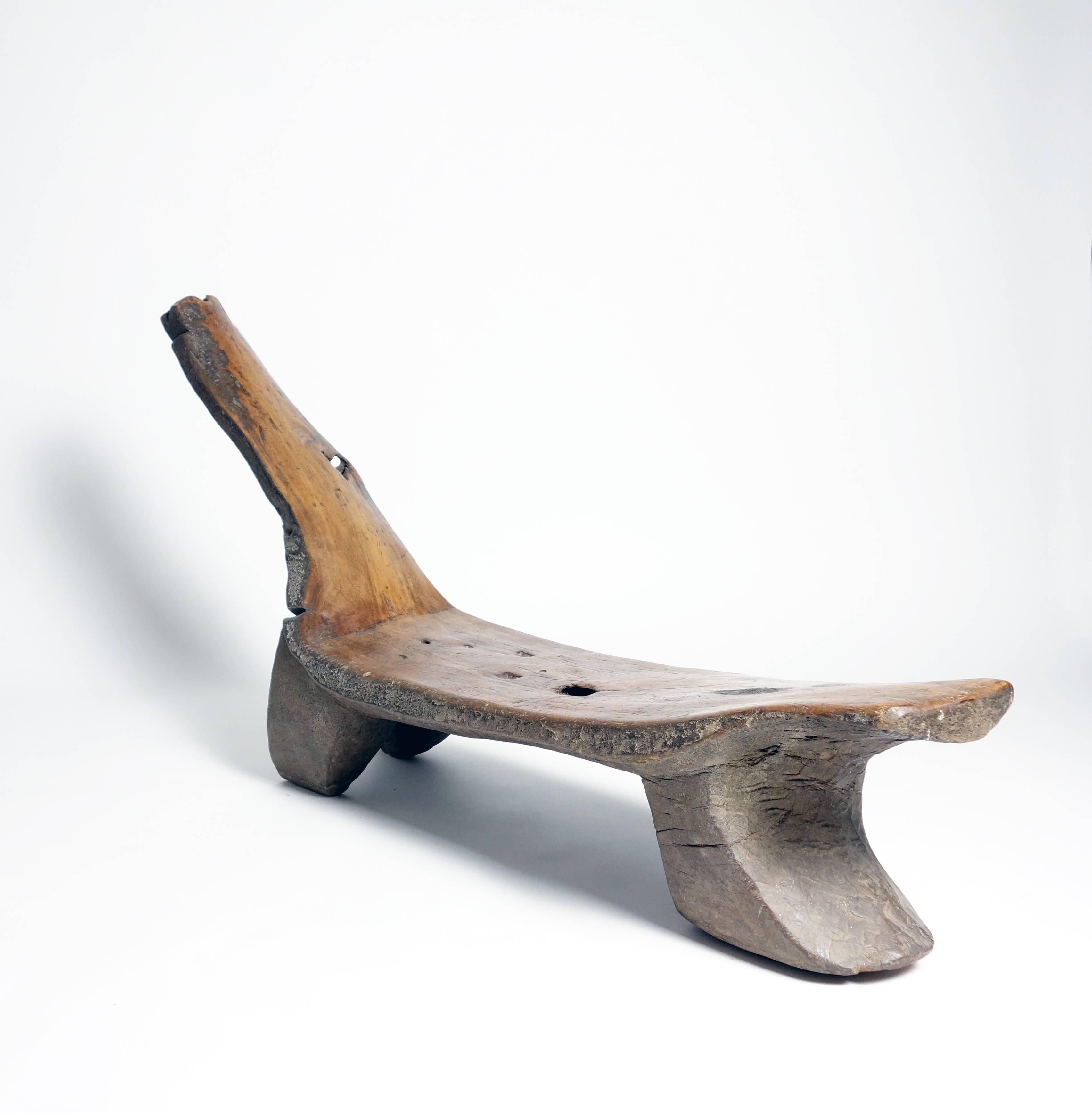 This dynamic daybed was carved of a single dense log, and its form seems to follow the growth habit of the tree. The seat and back are smooth with a fine and beautiful figuration and patina, the sides and bottom contrast with a rougher and darker