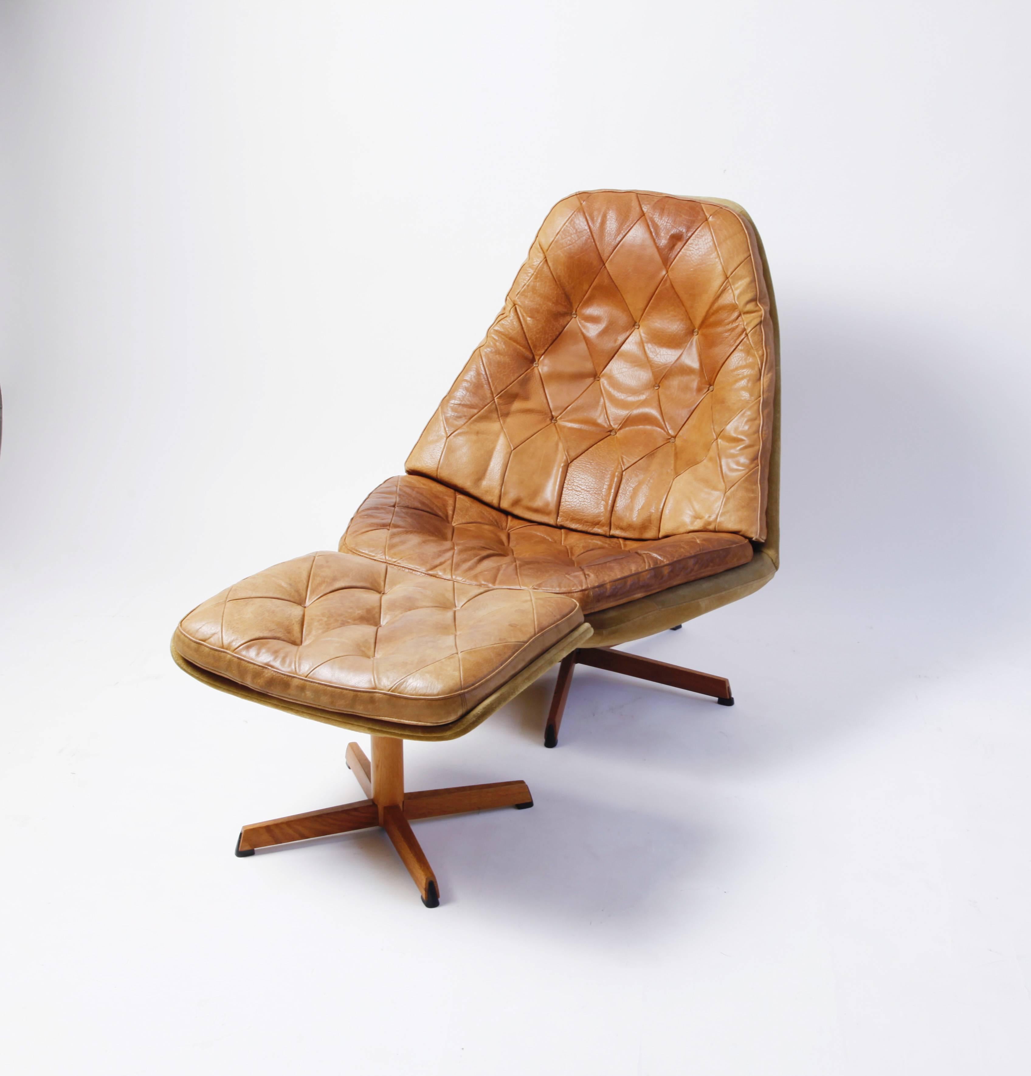 A handsome and exceedingly comfortable pair of 1960s Danish lounge chairs with matching ottomans by Acton Schubel and Ib Madsen (Model MS68). They are covered in beige suede, with tufted leather cushions (the patina is perfect) and bases of steel