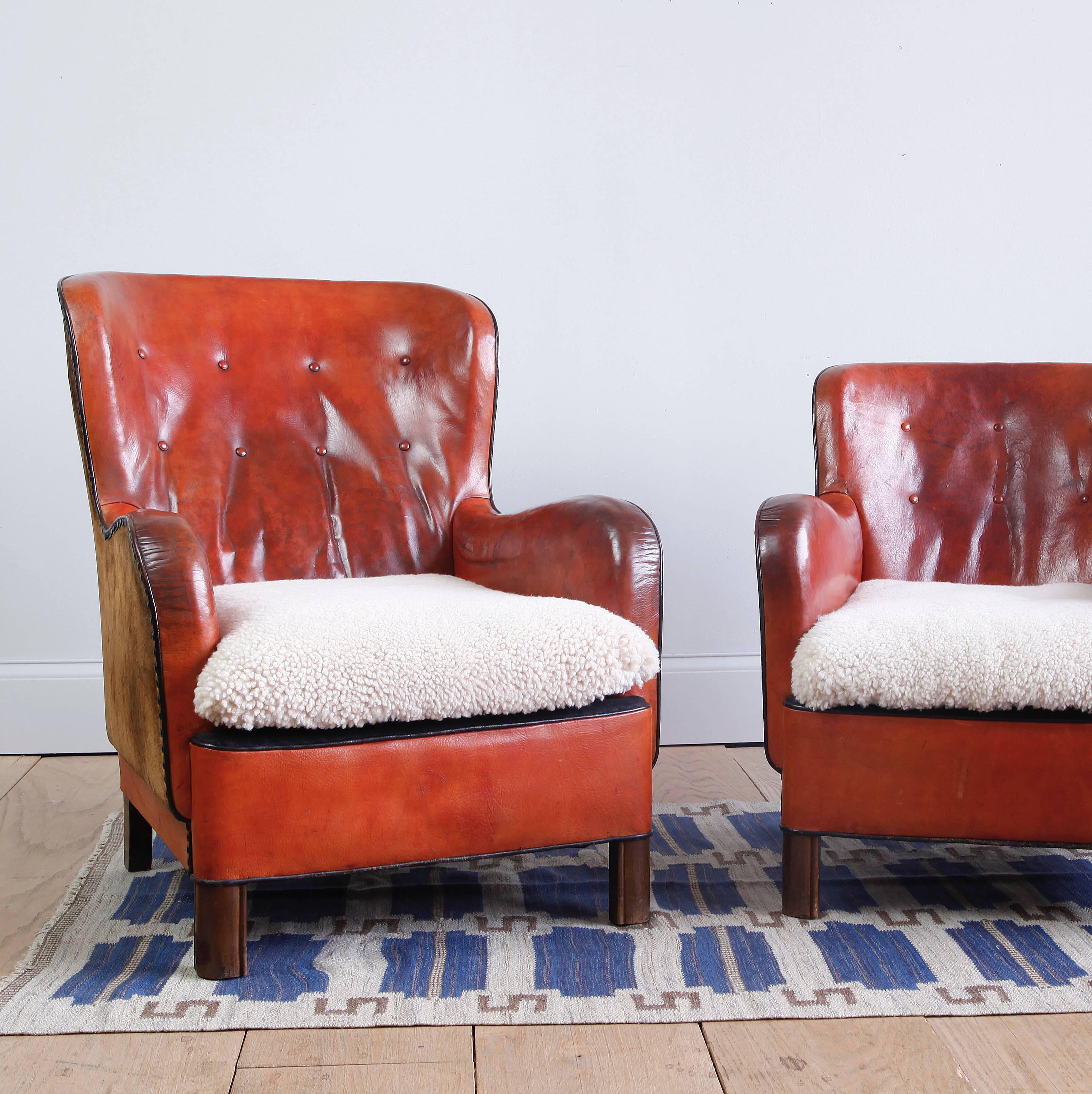 Two easy chairs by a highly skilled Danish cabinetmaker, in their original leather. The two different profiles one chair is visibly larger than the other, in 'mr. and mrs.' fashion--are in wonderful proportion to each other. The curve of the back