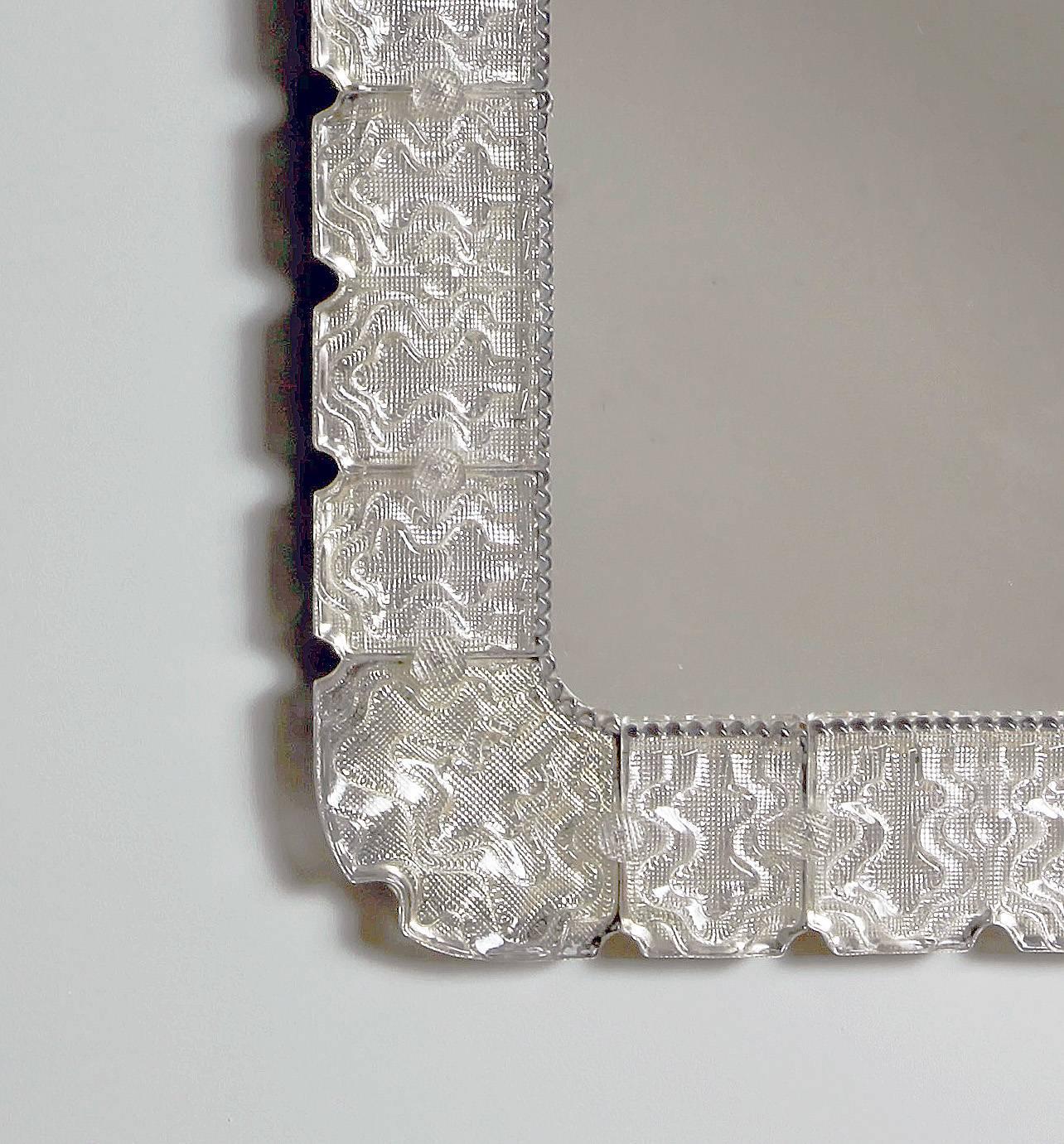 A large rectangular mirror with molded glass frame and beaded glass inner edge. The thick glass segments attached with glass buttons. Produced by Orrefors in the middle of the 20th century.