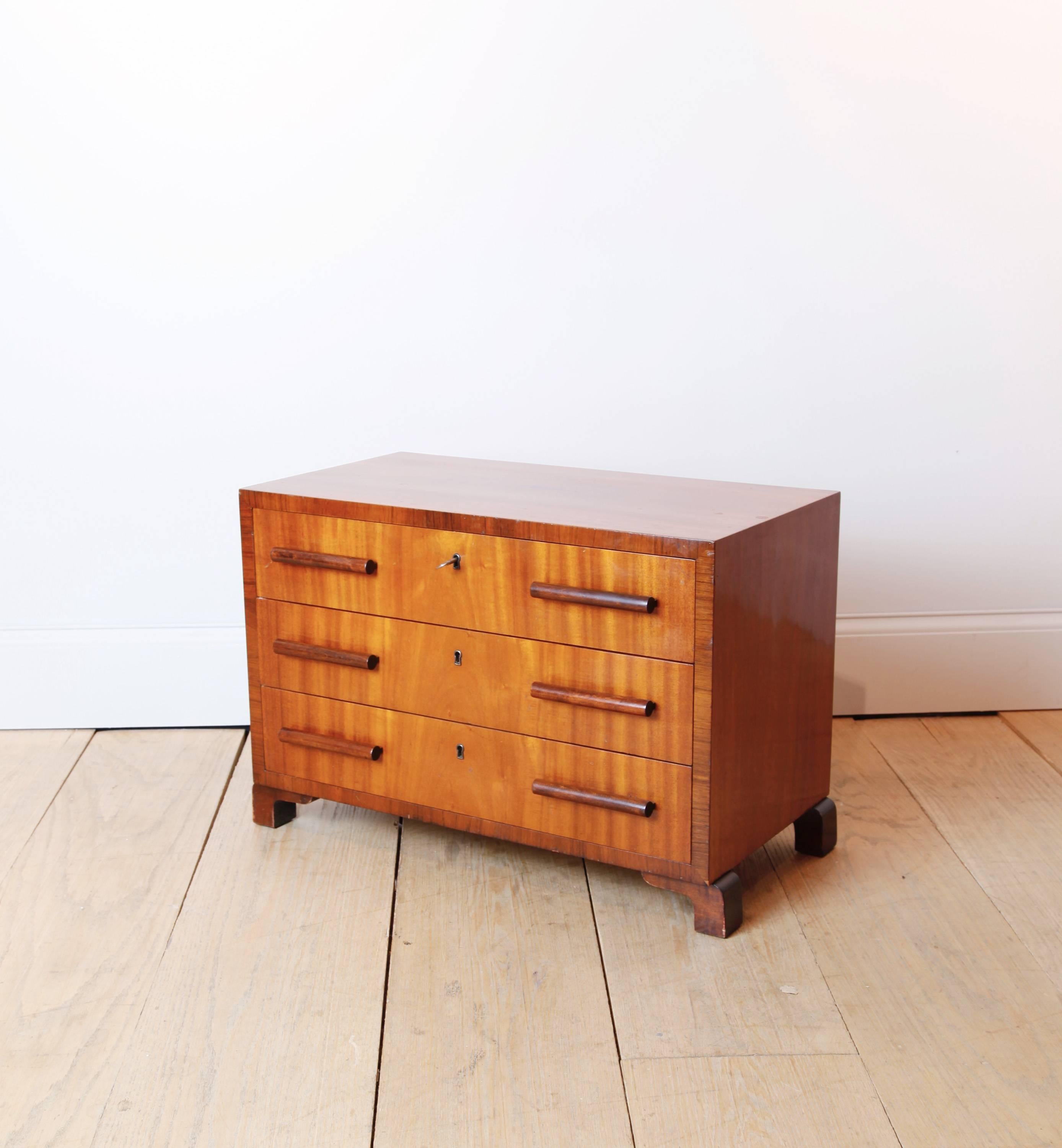 An exquisite small chest with three drawers, of mahogany and rosewood. Its proportions make it eminently suitable as a side table.